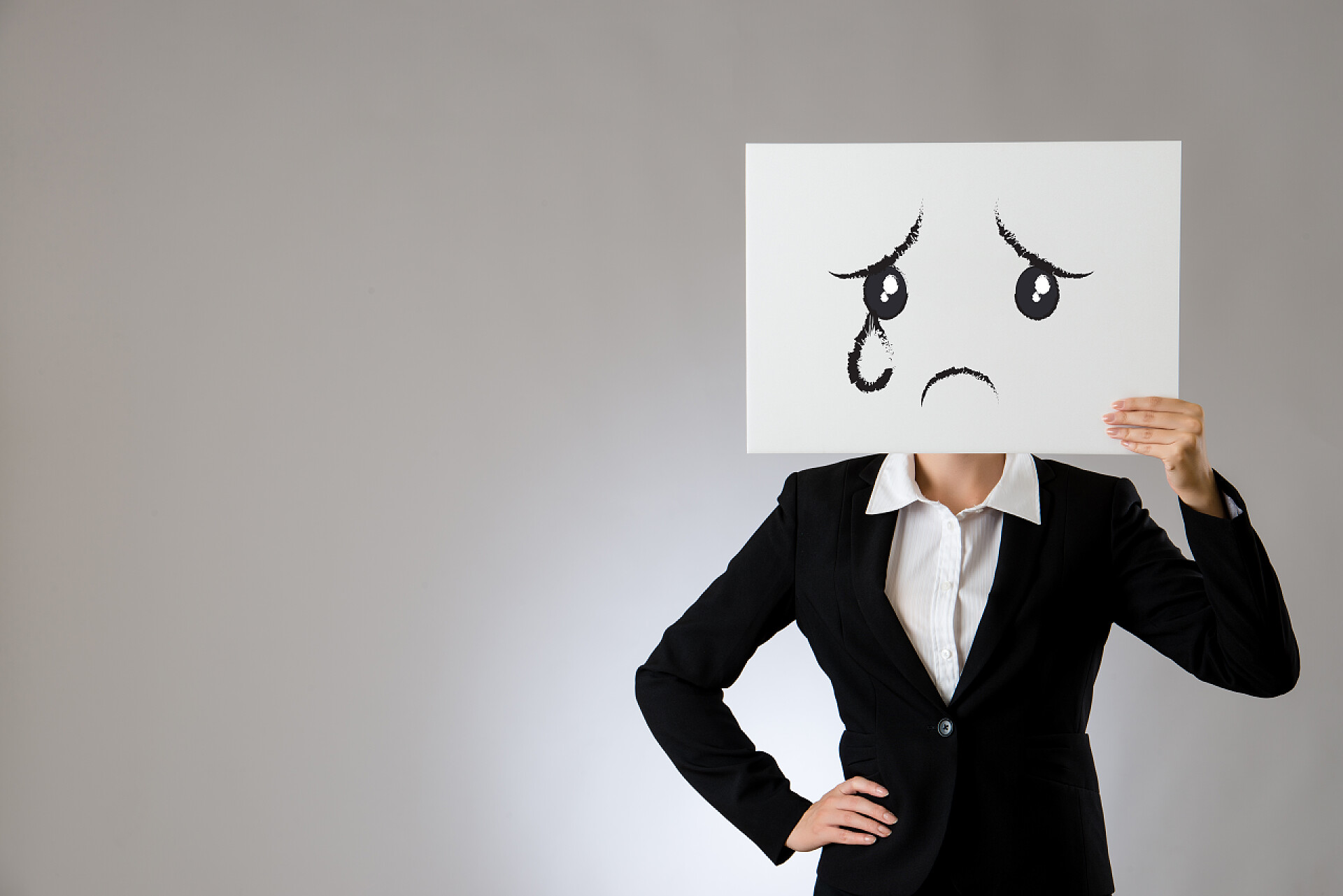 企业老板拿着画有悲伤哭脸图的白板抱着空白白板与悲伤和哭泣