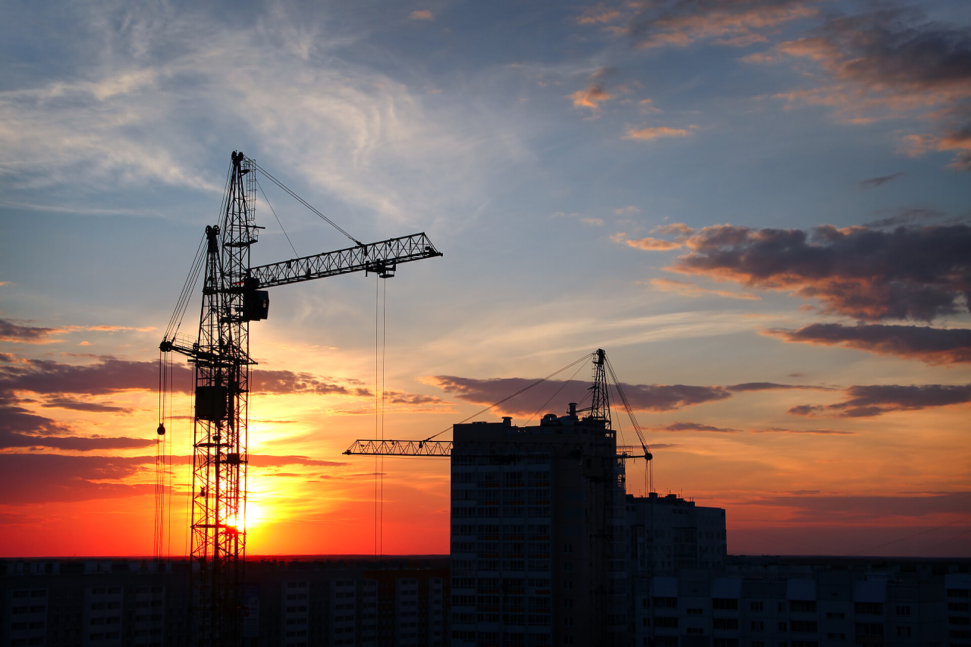城市剪影傍晚的天空背景下的塔式起重机在城市的塔式起重机