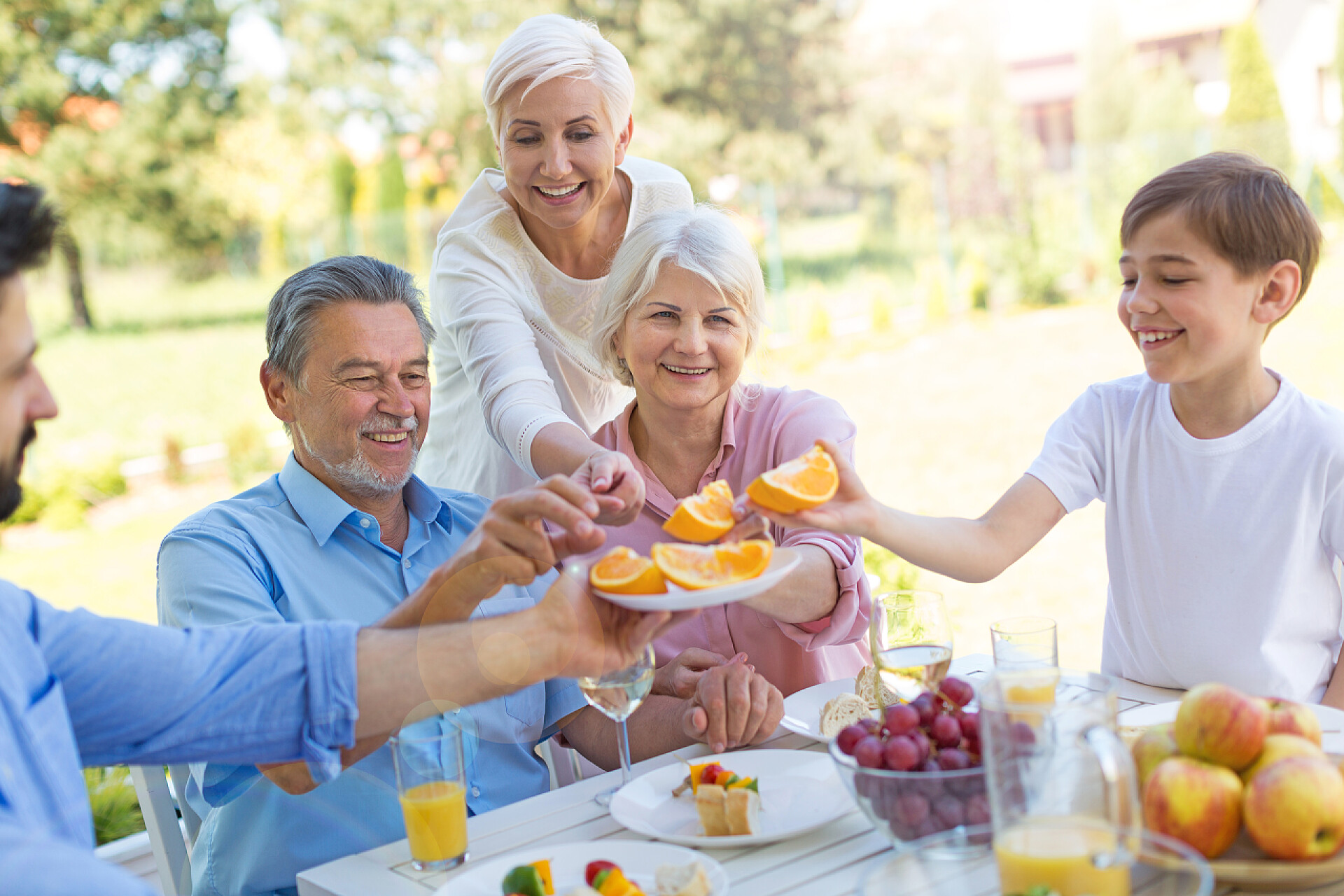 家庭坐在花园里开心聚餐大家庭在户外吃