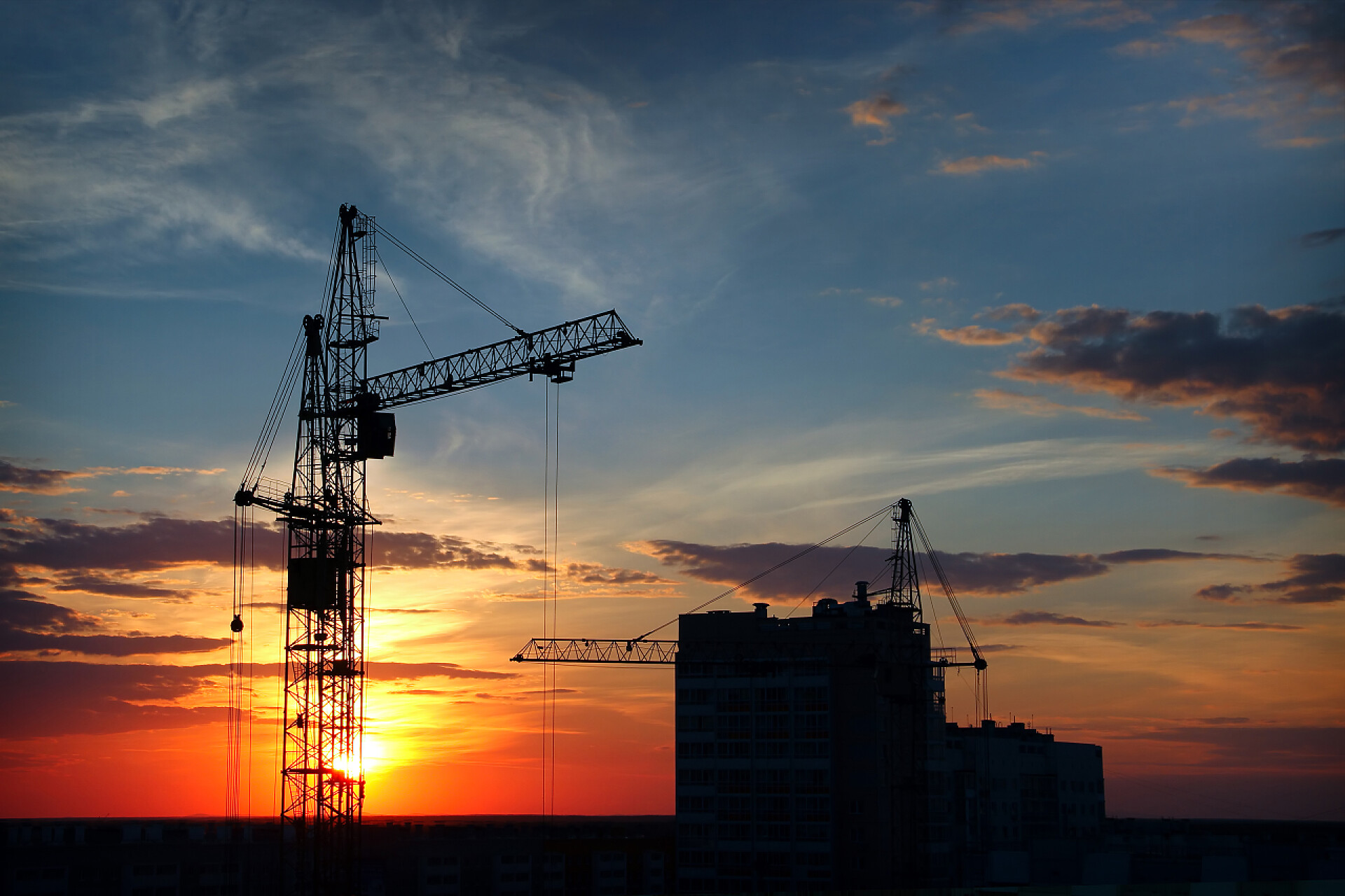 傍晚的天空背景上工作的起重机塔式起重机的剪影