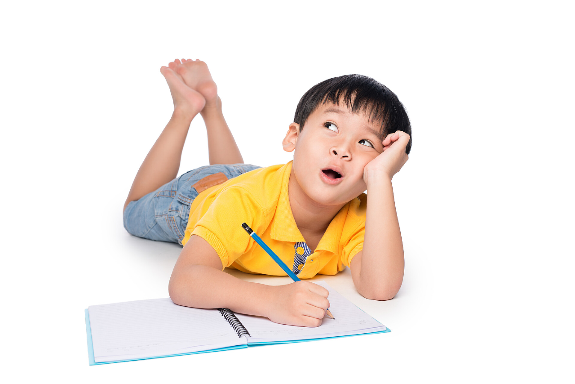 趴在白色背景上的小男孩在思考问题小学生写在笔记本上.