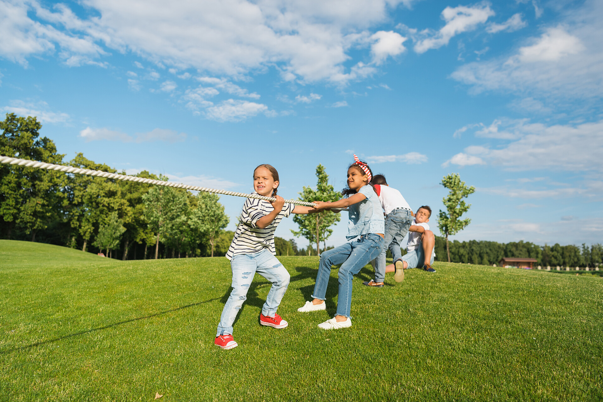 蓝天下一群孩子在草地上玩拔河玩拔河游戏的儿童