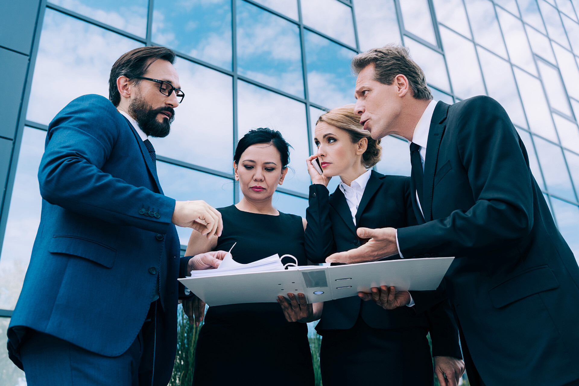 多个商人在公司大楼附近讨论问题多民族商人讨论文件 