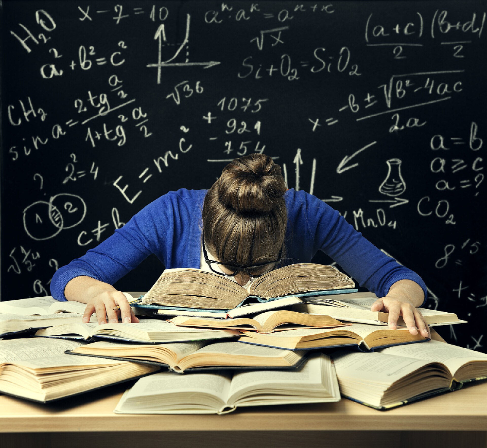 女人低头趴在一堆翻开的书上学生努力学习，厌倦了无聊的女人阅读书籍在黑板