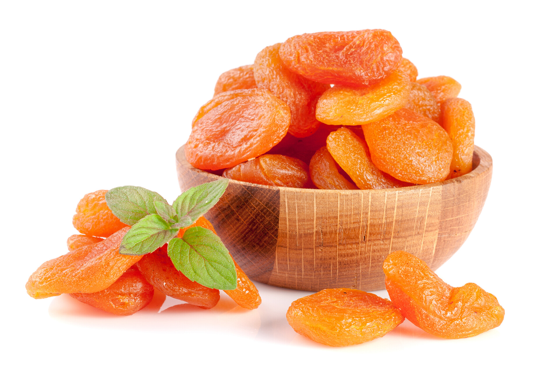 白色背景下一碗杏干在一个木碗用薄荷叶上 whi 孤立杏干