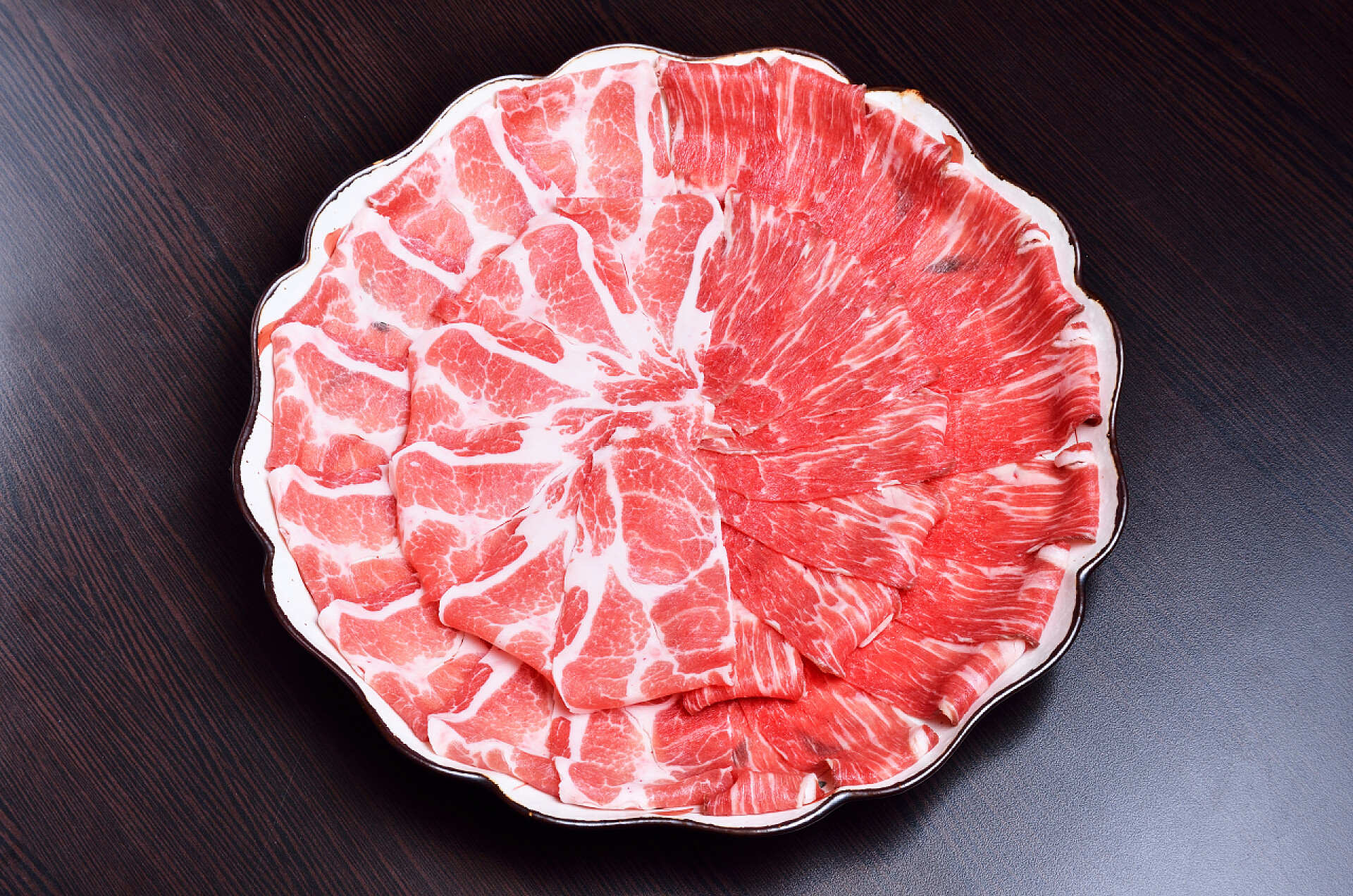 黑色背景上一盘猪肉切片在板上的生猪肉片