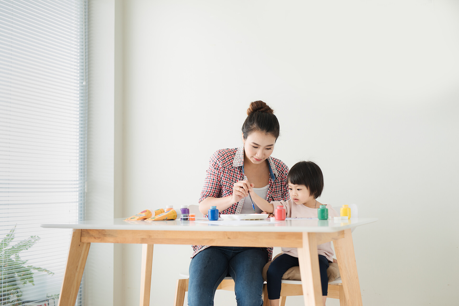 母亲和小女儿一起坐在桌旁绘画母亲和女儿绘画