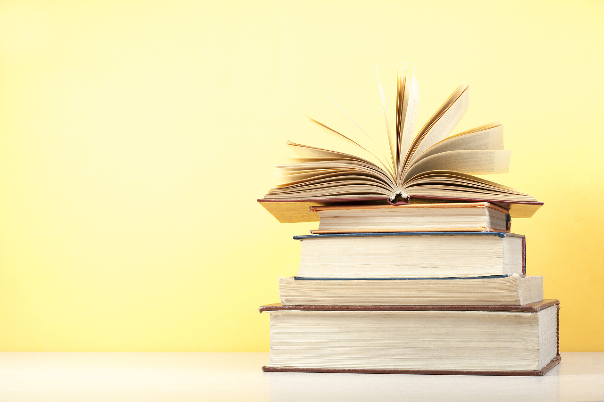 黄色背景下木制的桌子上打开的书打开的书，精装书木制的桌子上。教育背景。回到学校。复制文本的空间.