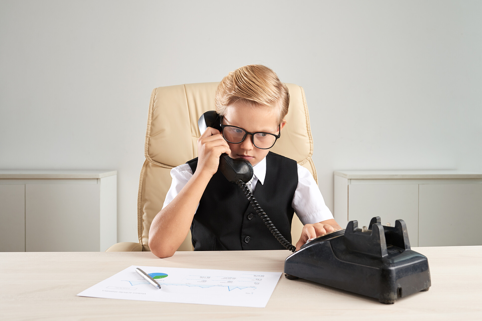 小男孩在课桌前打电话男企业家在他的桌上打电话