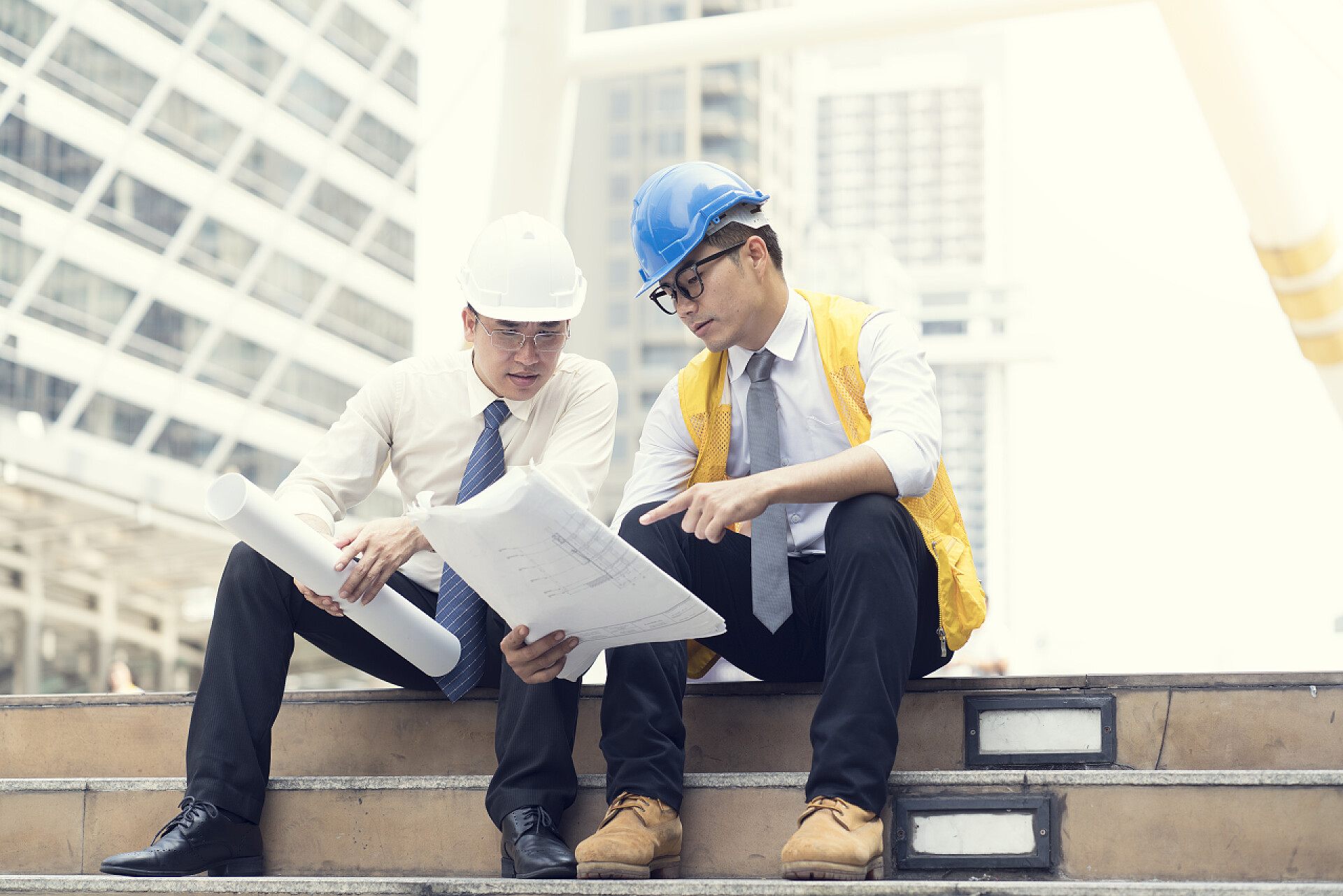 建筑策划师坐在楼梯上聊项目场景亚洲工程师一起咨询, 并计划在建设