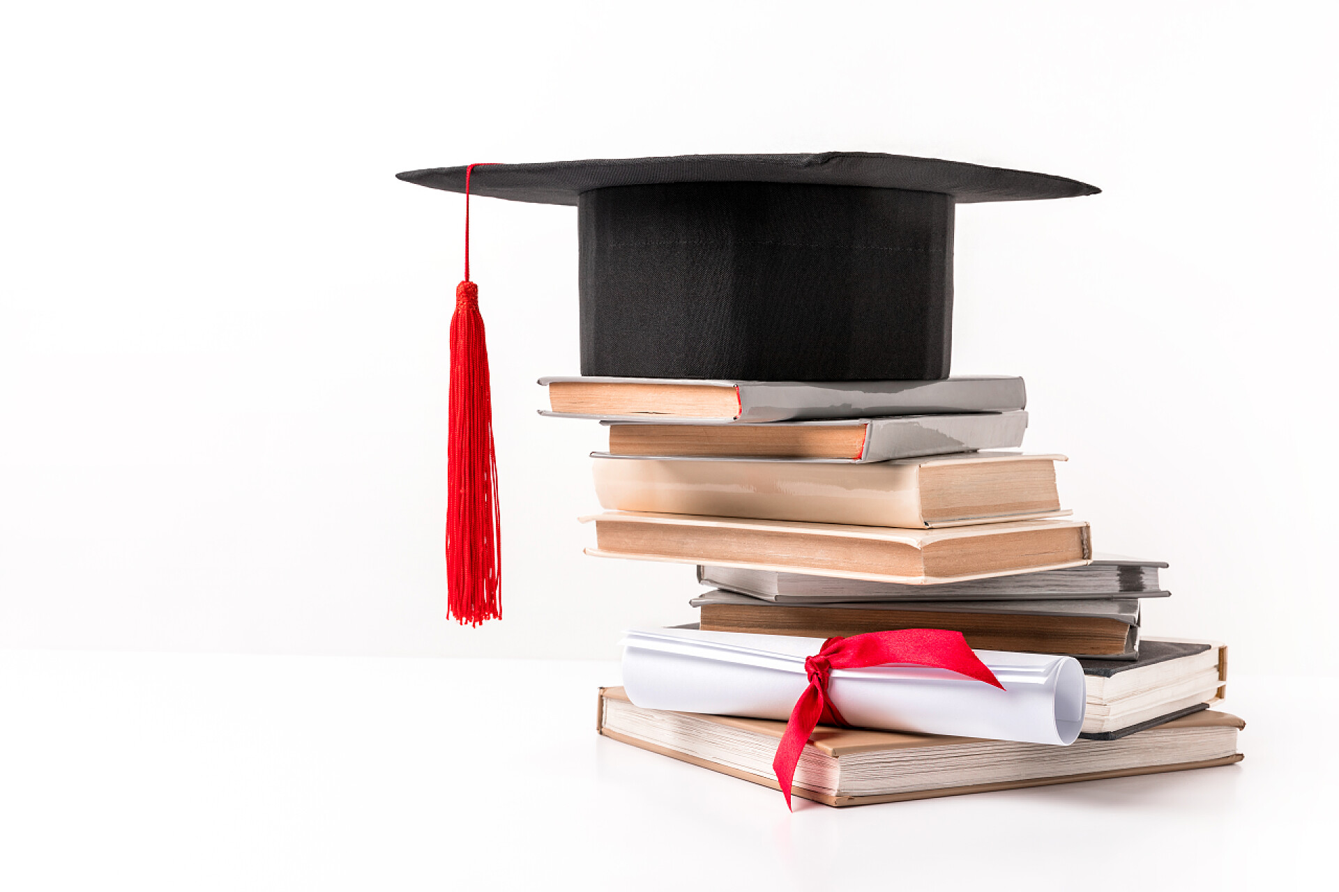 学位帽和一摞书学术盖帽在白色被隔绝的书栈