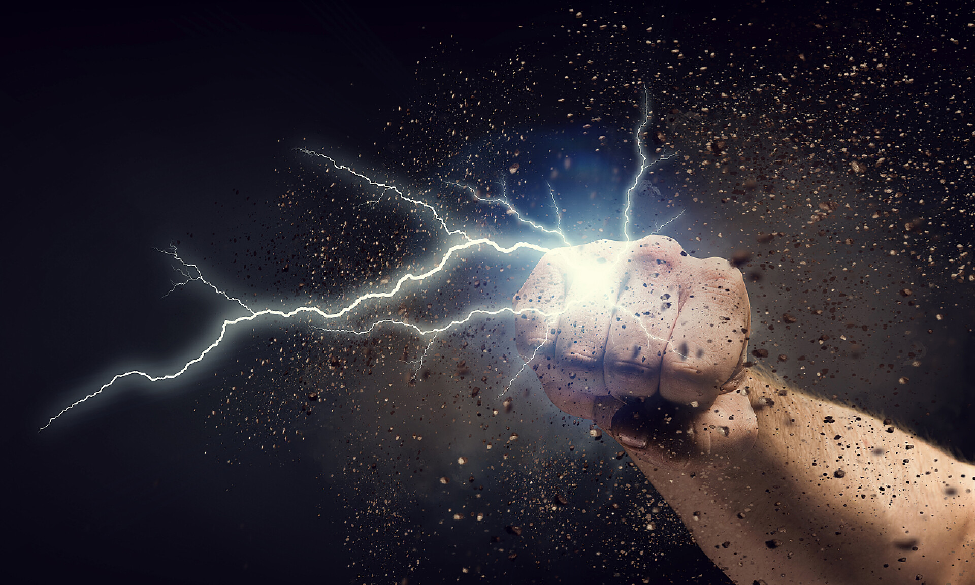 黑色背景下拳头和裂纹冲破墙上的手。混合媒体