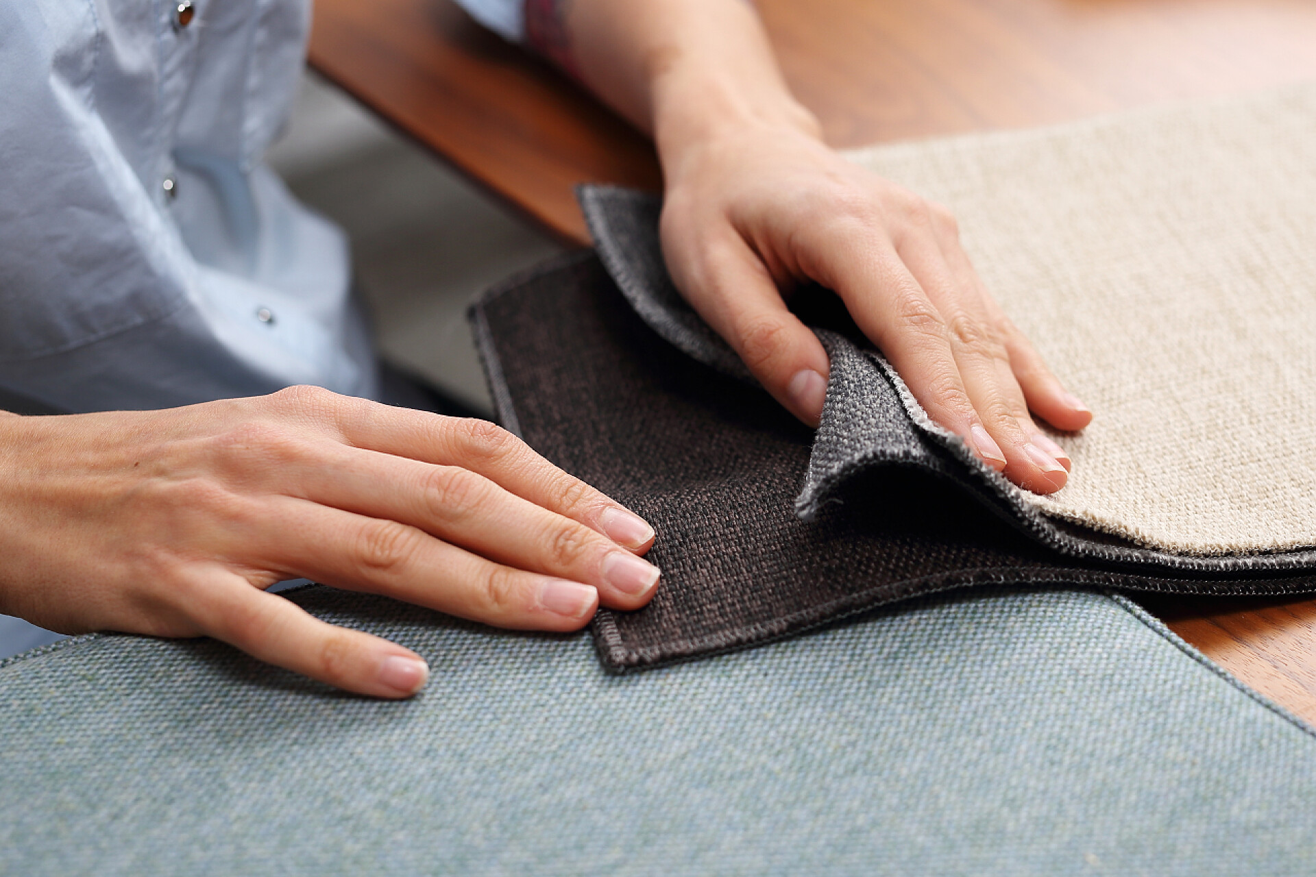 局部特写正在挑选沙发布料购物沙发, 选择色彩装潢。女人看着装饰面料的颜色和图案.