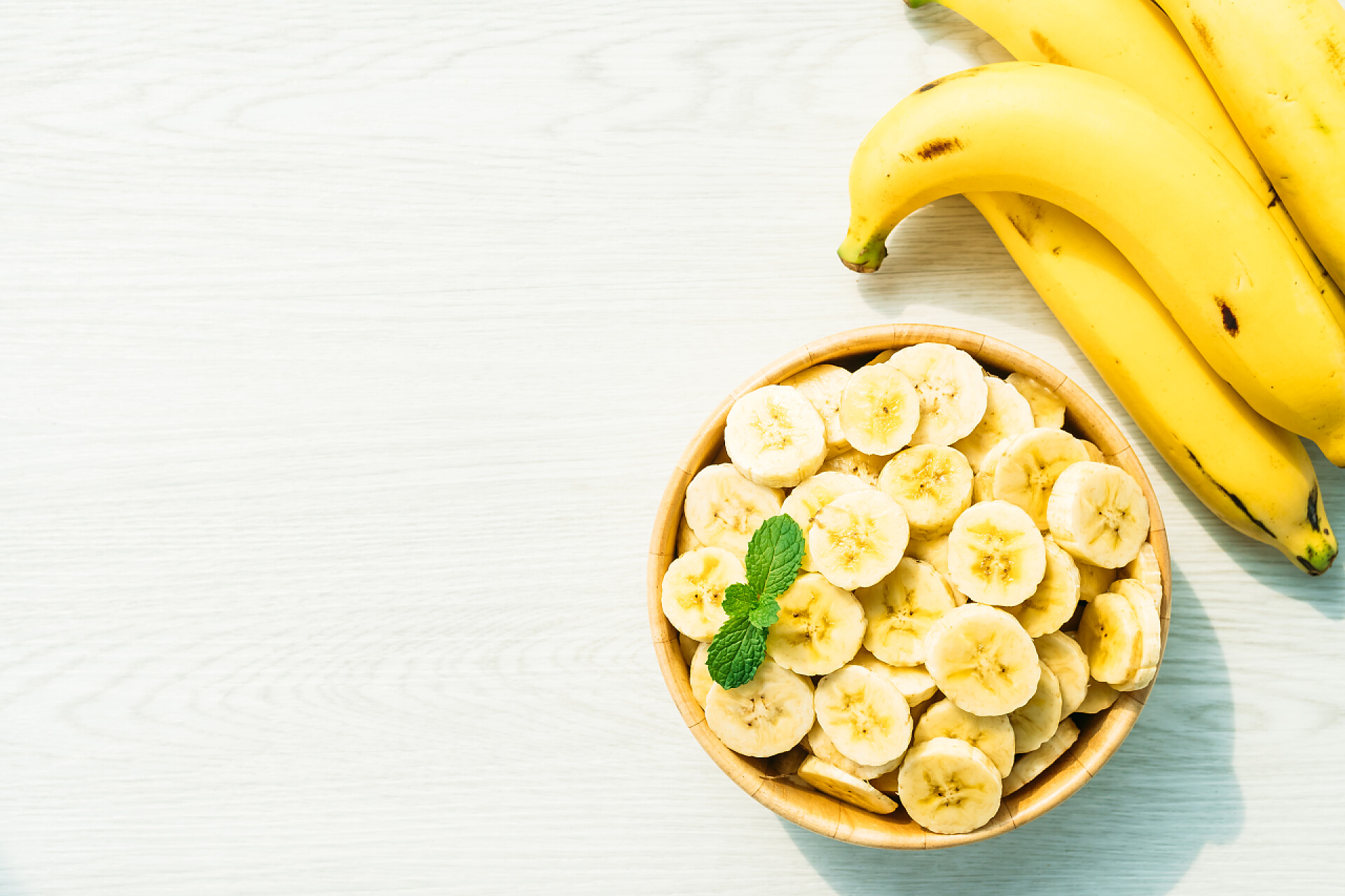 在米色木纹桌子上的香蕉片和香蕉木碗生黄香蕉片