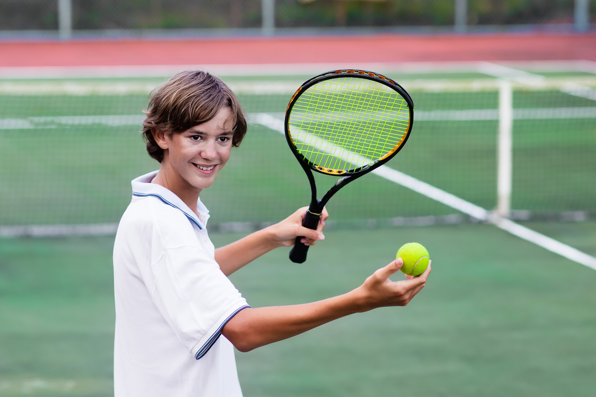 男孩在室外篮球场上打网球在室外篮球场上打网球的孩子