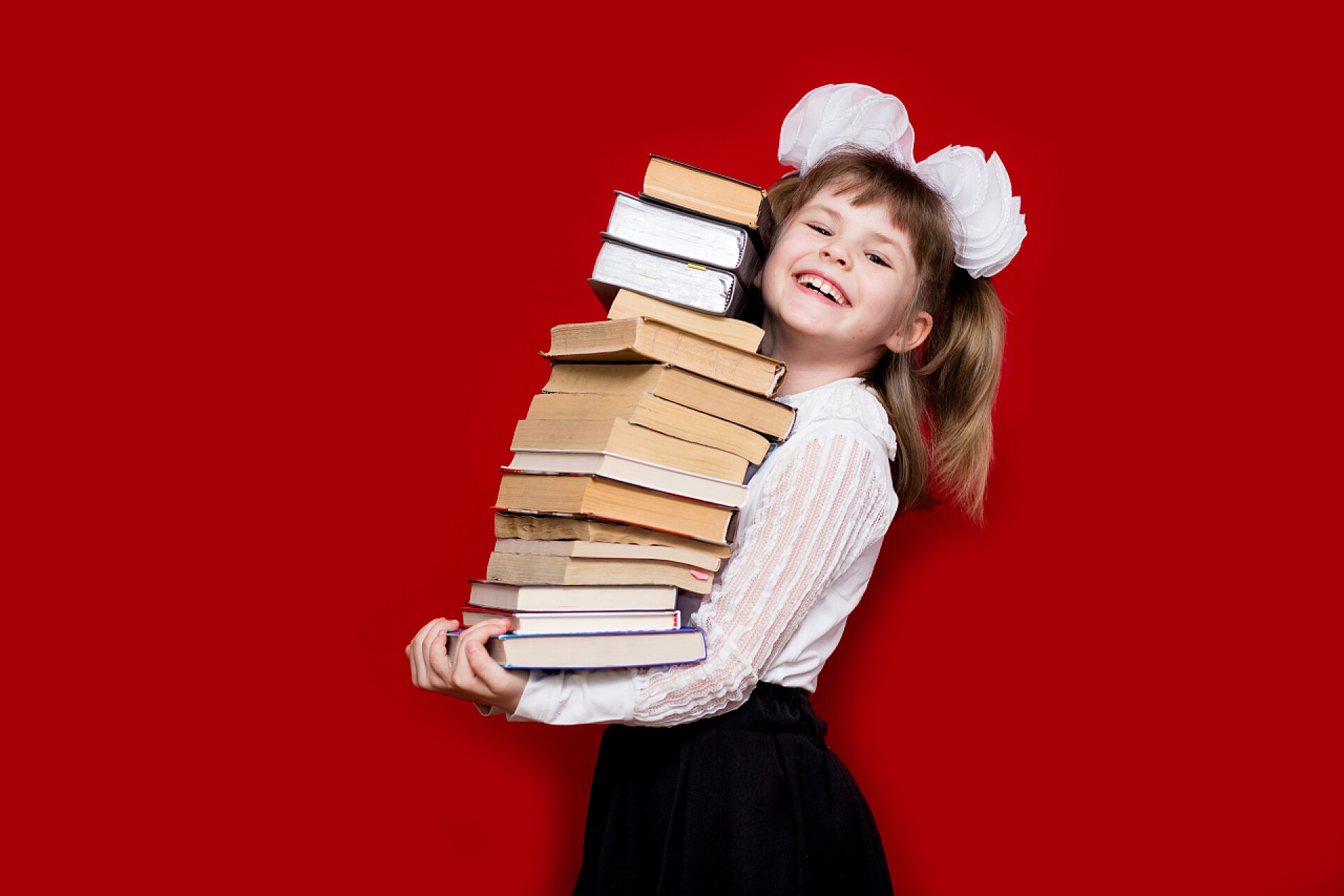小女孩抱着许多的书小女孩把许多书都用红色隔开了。知识或学校的概念。书恋人