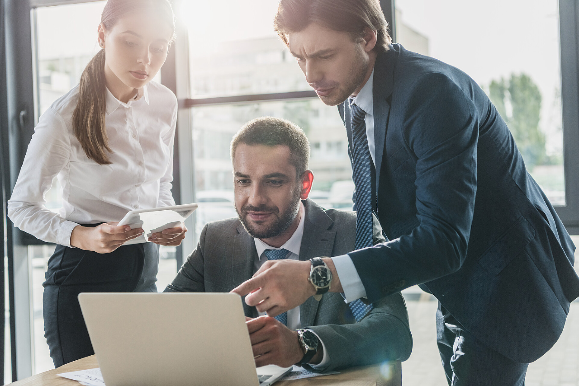 带着手提电脑在办公室微笑的生意人成功的商务人士使用膝上型电脑在现代办公室