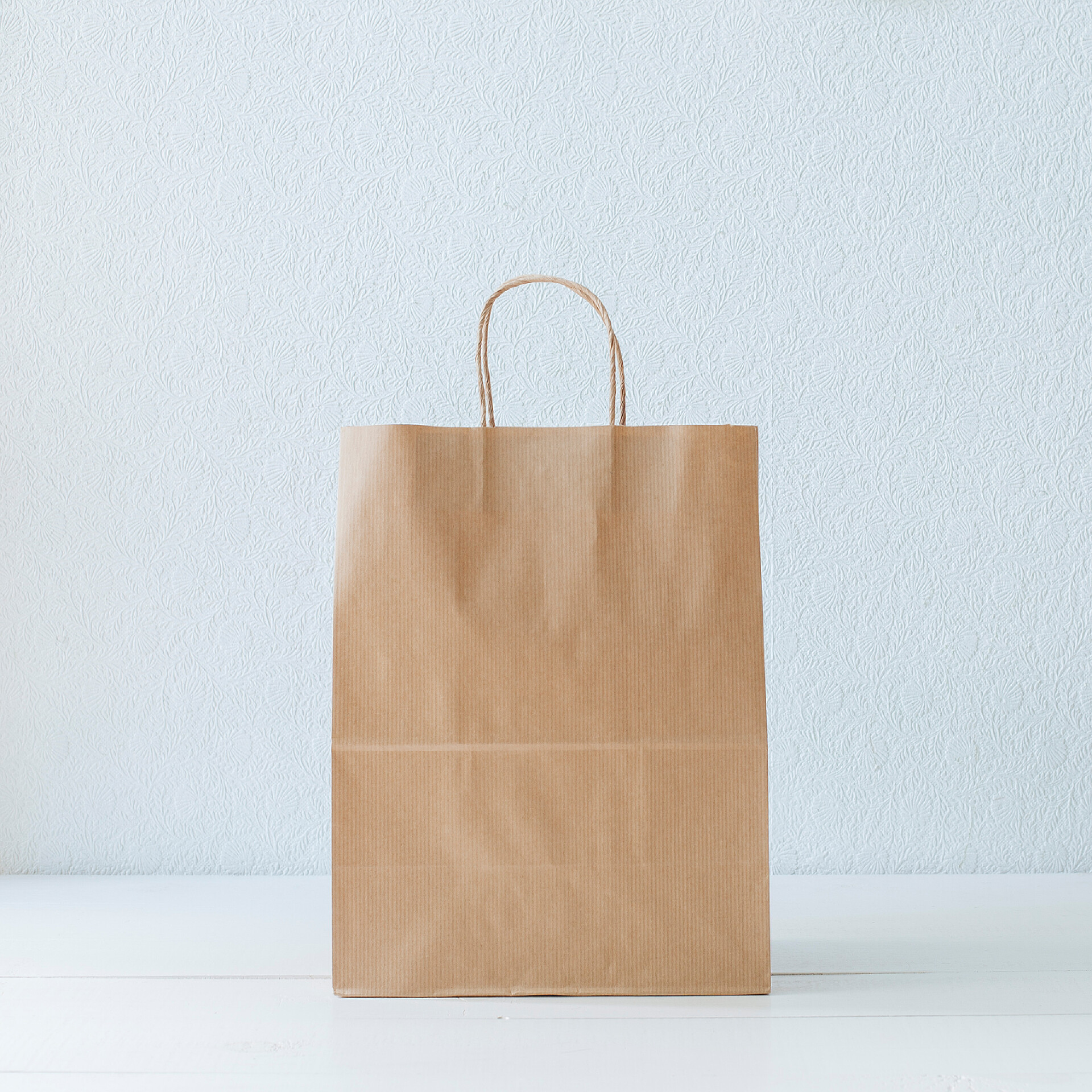 白色背景下的一个纸袋纸袋。白色的桌子。白色壁纸.