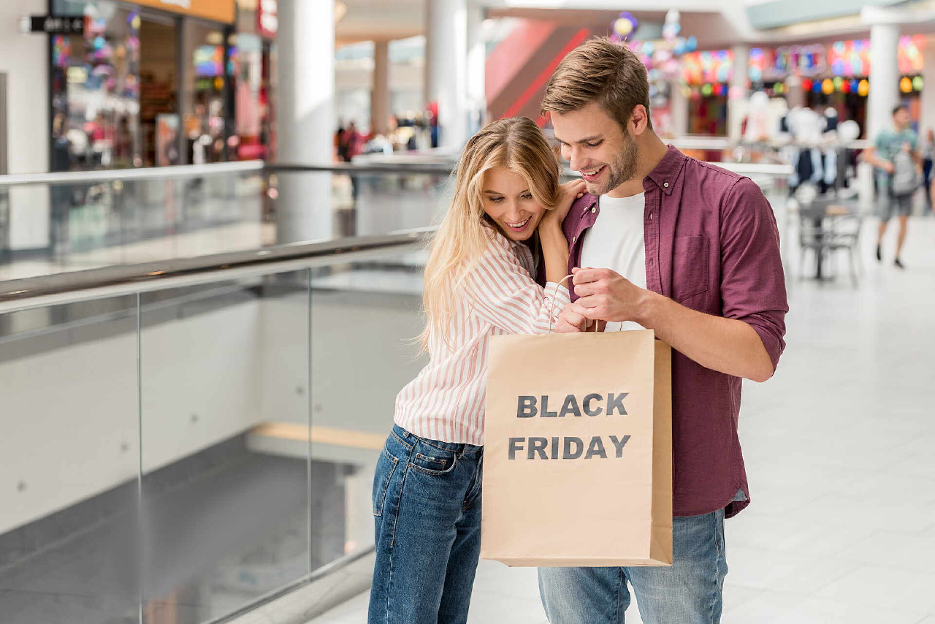 情侣在商场购物年轻夫妇的购物者向下看和手持纸袋黑色星期五在购物中心 