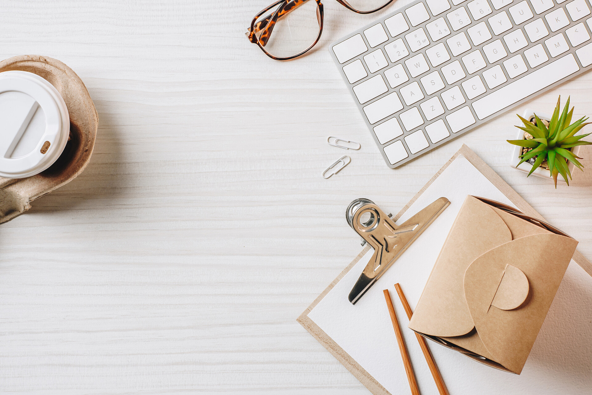 桌子上摆放着纸咖啡杯锅盒筷子和电脑键盘平躺在桌子上的纸咖啡杯, 锅盒, 筷子和电脑键盘在办公室 