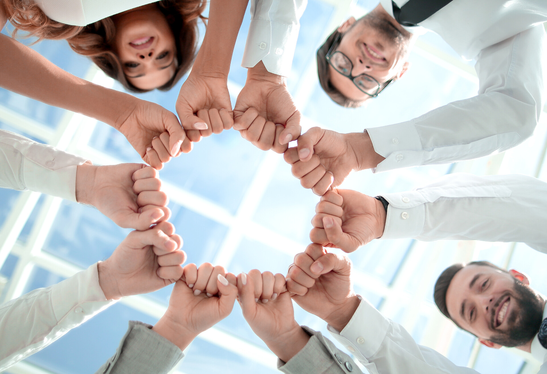 商务团队用拳头组成一个圆圈底视图底部视图。业务团队站在一个圈子里.