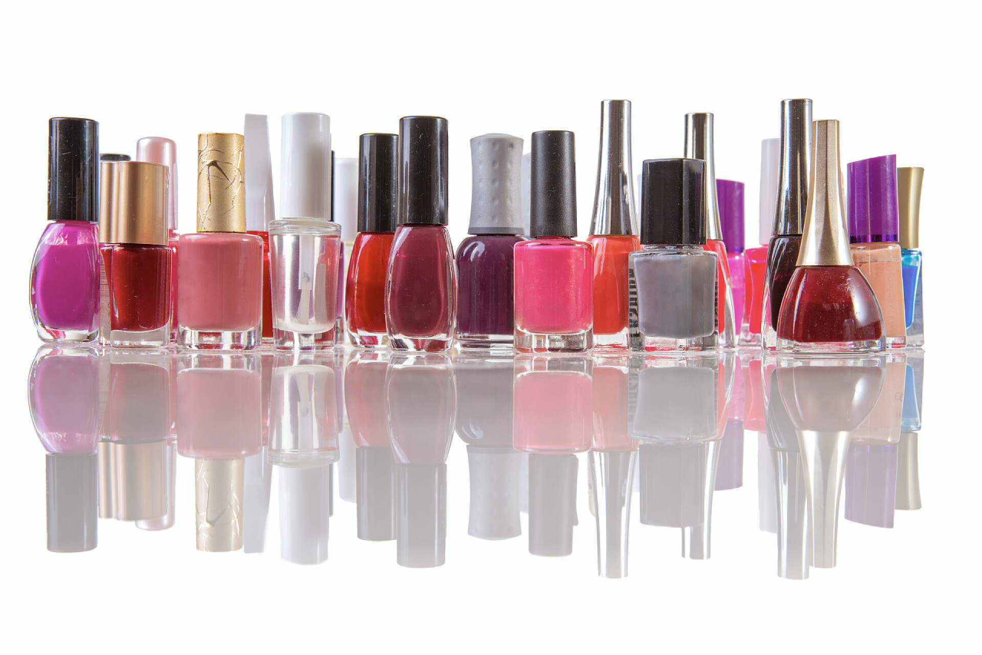 白色背景上光亮的桌面上放着一排彩色的指甲油彩色指甲抛光在一个孤立的白色背景与反射