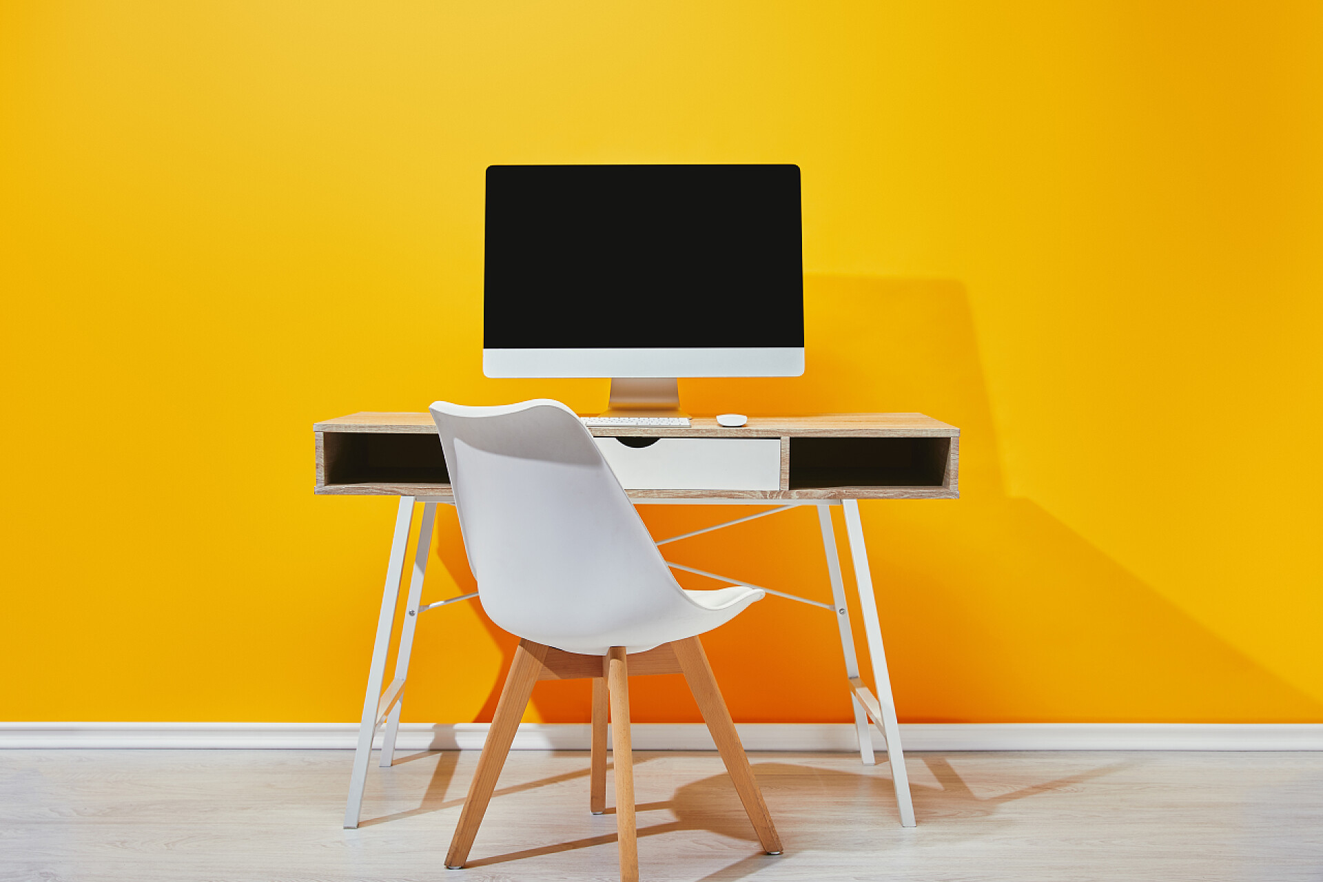 黄色背景前的空白屏幕电脑在靠近黄色墙壁的工作场所使用电脑、相框和仙人掌