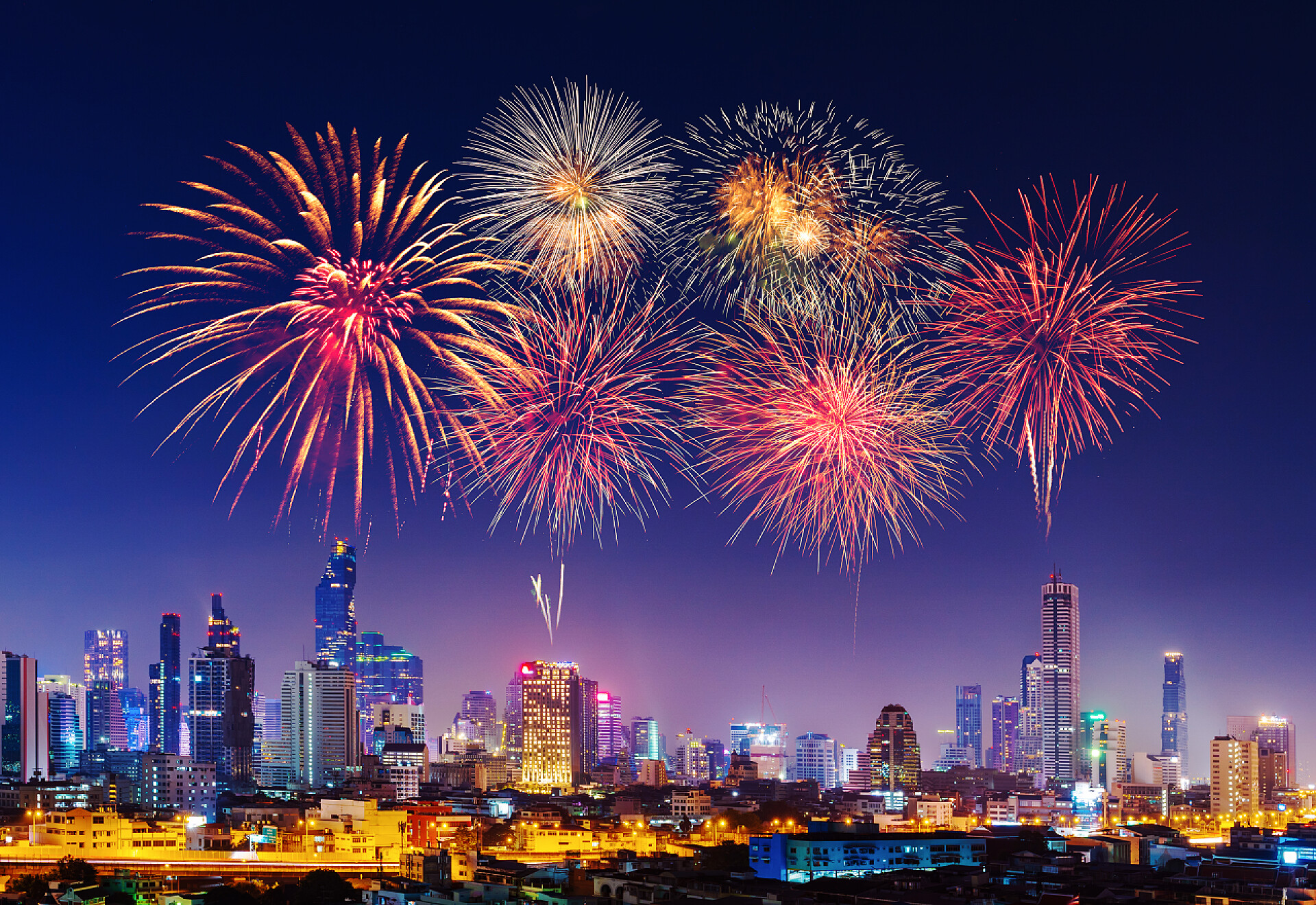 夜晚城市天空中绽放的烟花快乐的新年烟花闪耀与乐队角城市景观在夜间