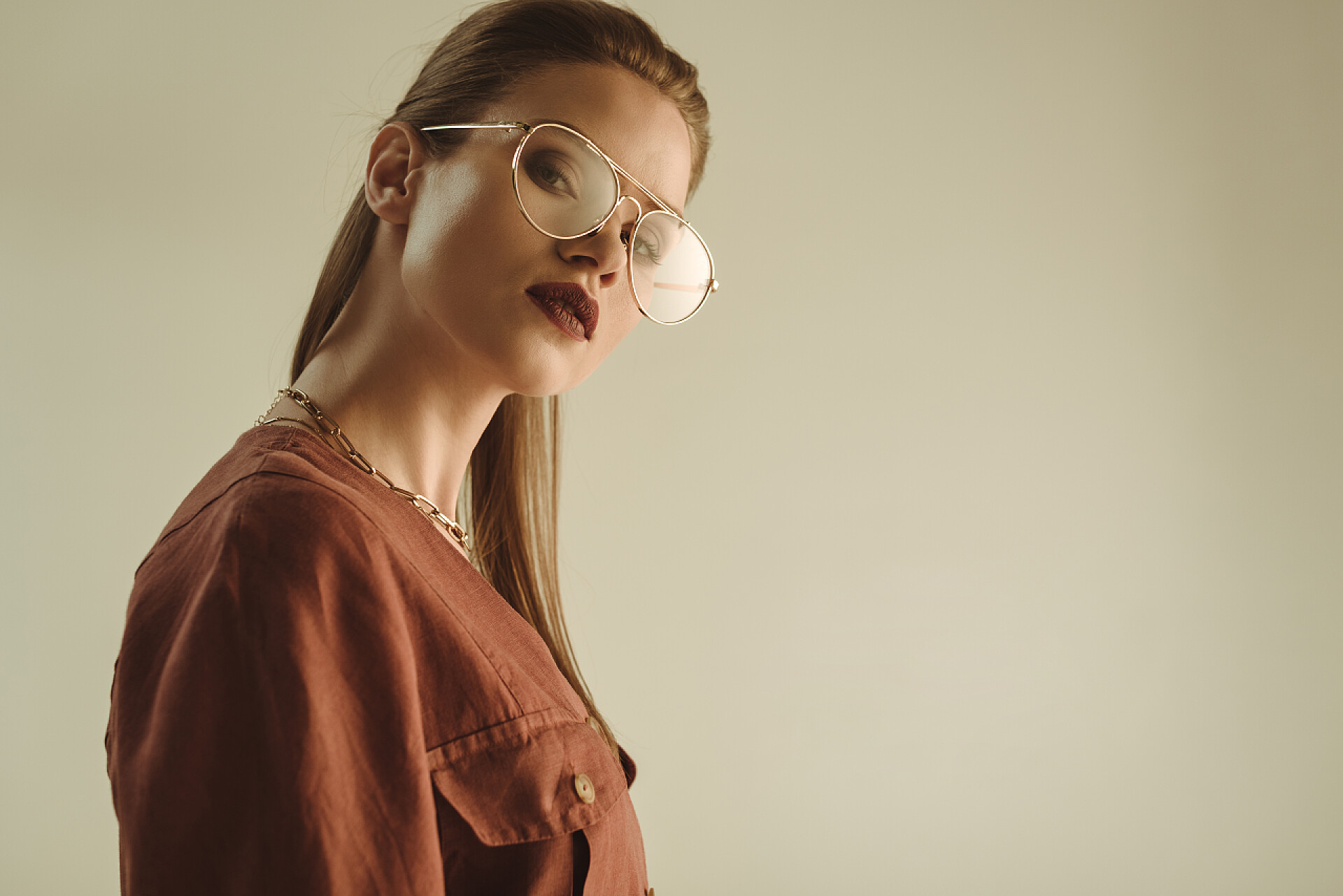 米色背景戴棕色眼镜的时尚女模特美丽的时尚女孩摆在时尚的眼镜孤立在米色