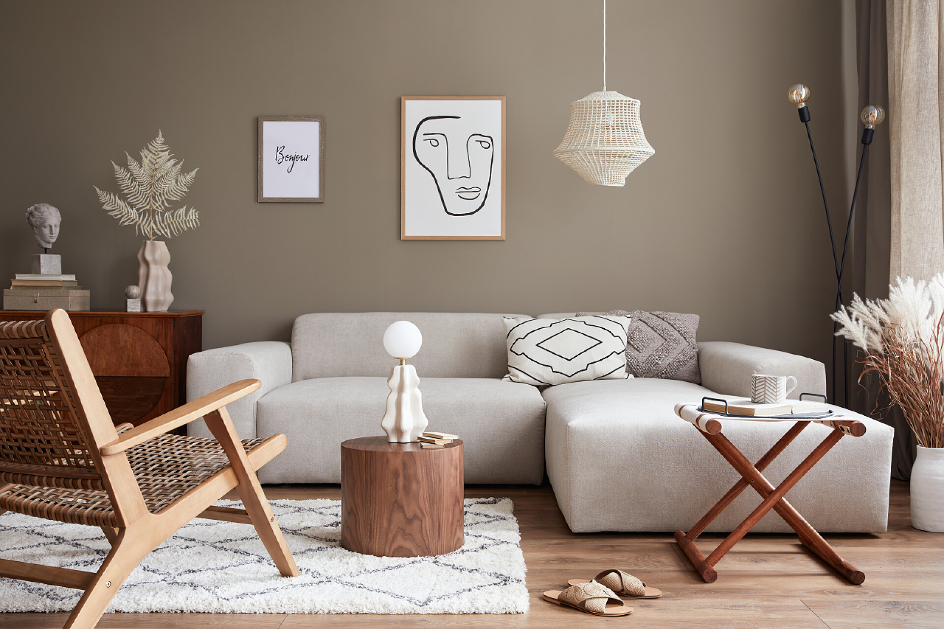 室内客厅全景展示图时尚的室内装饰，设计中性模块化沙发，造型海报框架，藤椅，咖啡桌，花瓶中的干花，装饰和雅致的个人配饰在现代家居装饰.