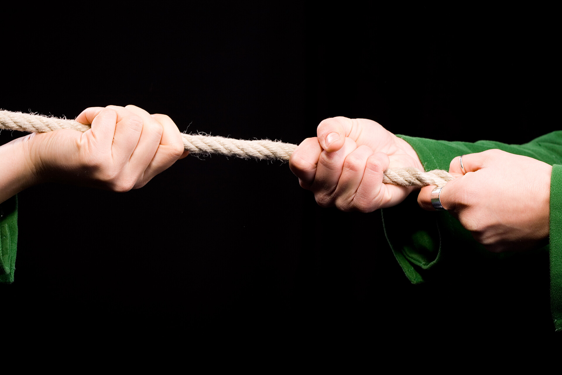 黑色背景上两双手在拉扯绳子拔河 cloeseup