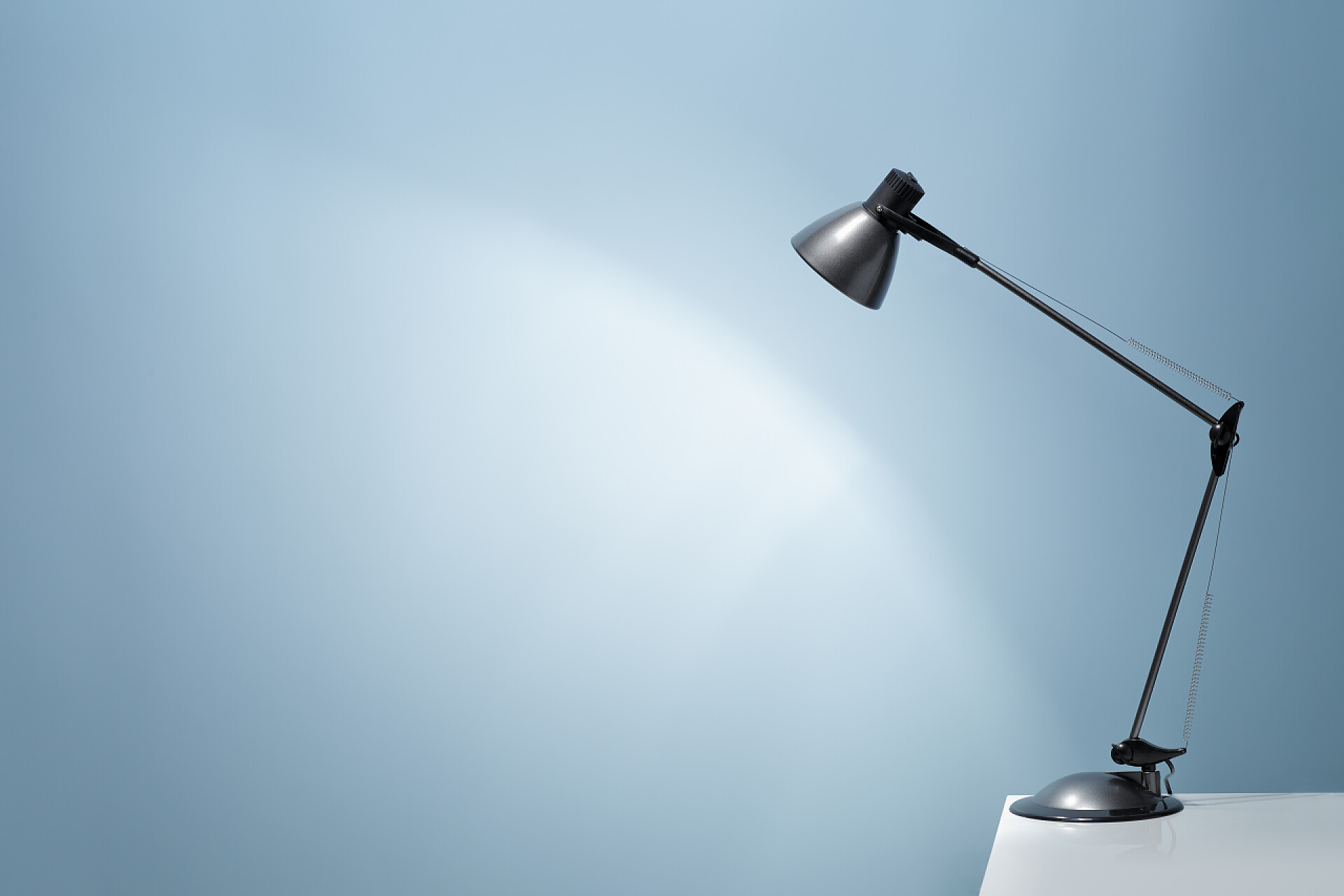 打开办公桌的台灯照在蓝墙上台灯