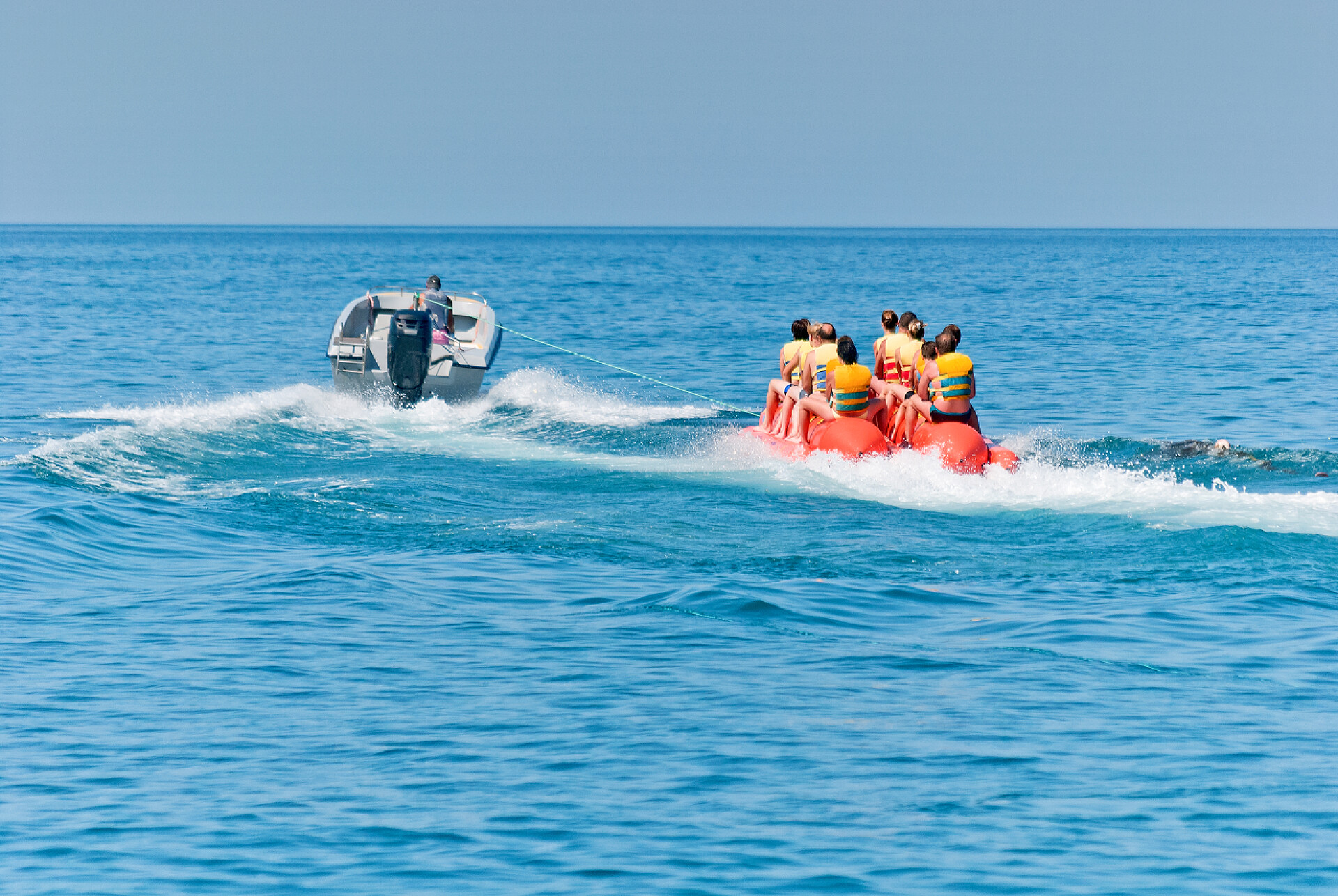 海洋里划船的游客在空气香蕉上滑冰