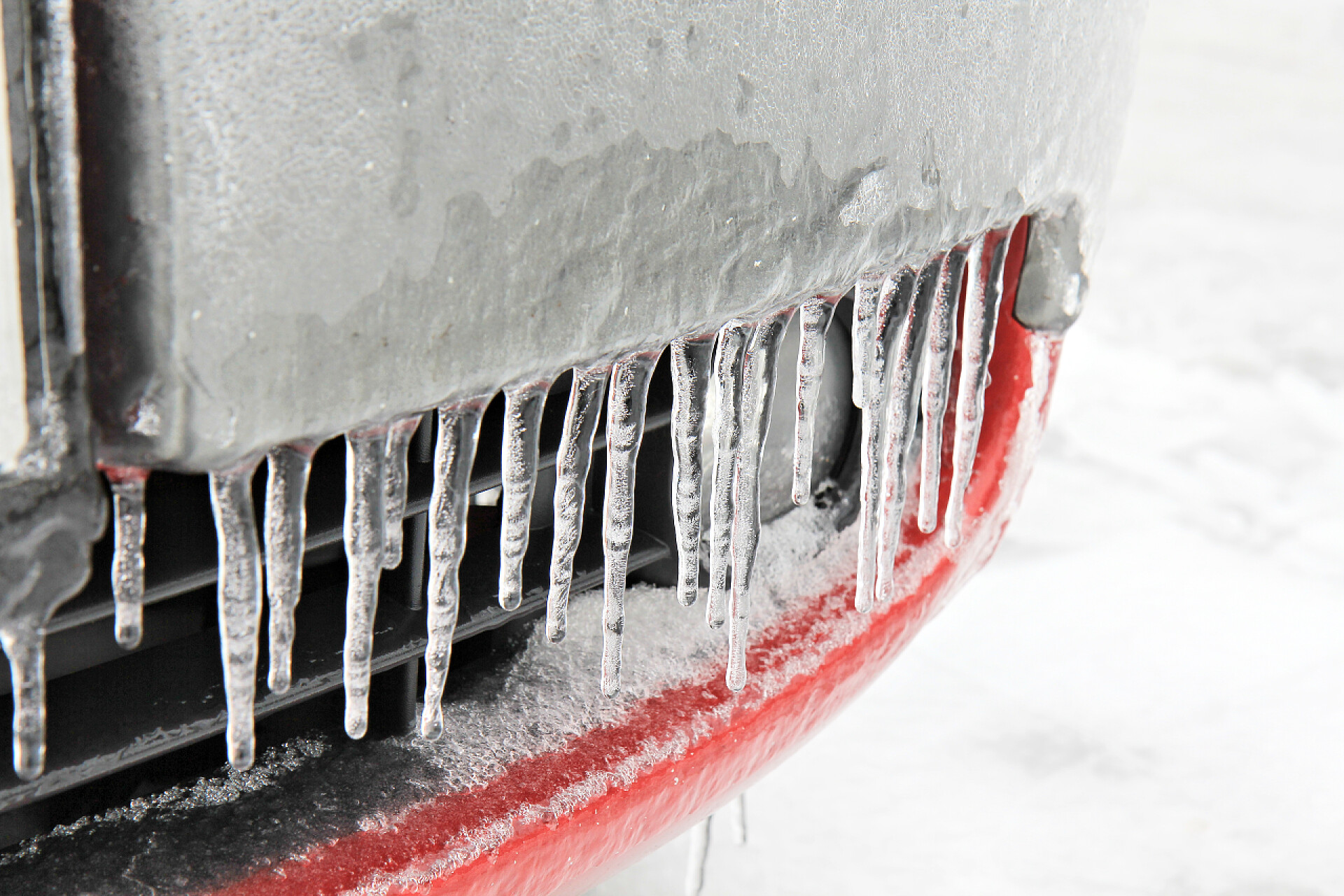 结冰的红色汽车保险杠红色汽车保险杠上的冰柱