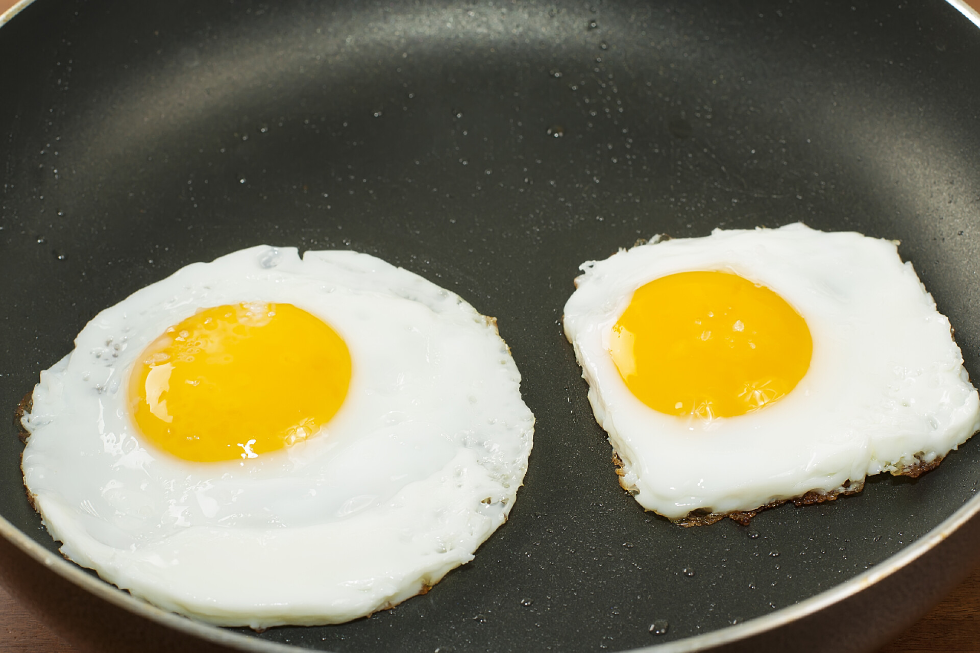 平底锅中两个不同形状的煎蛋炒煎的鸡蛋，经典烹饪