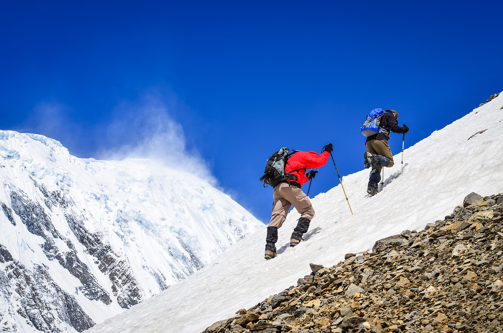 两个游客徒步登雪山两山徒步上积雪的山峰背景