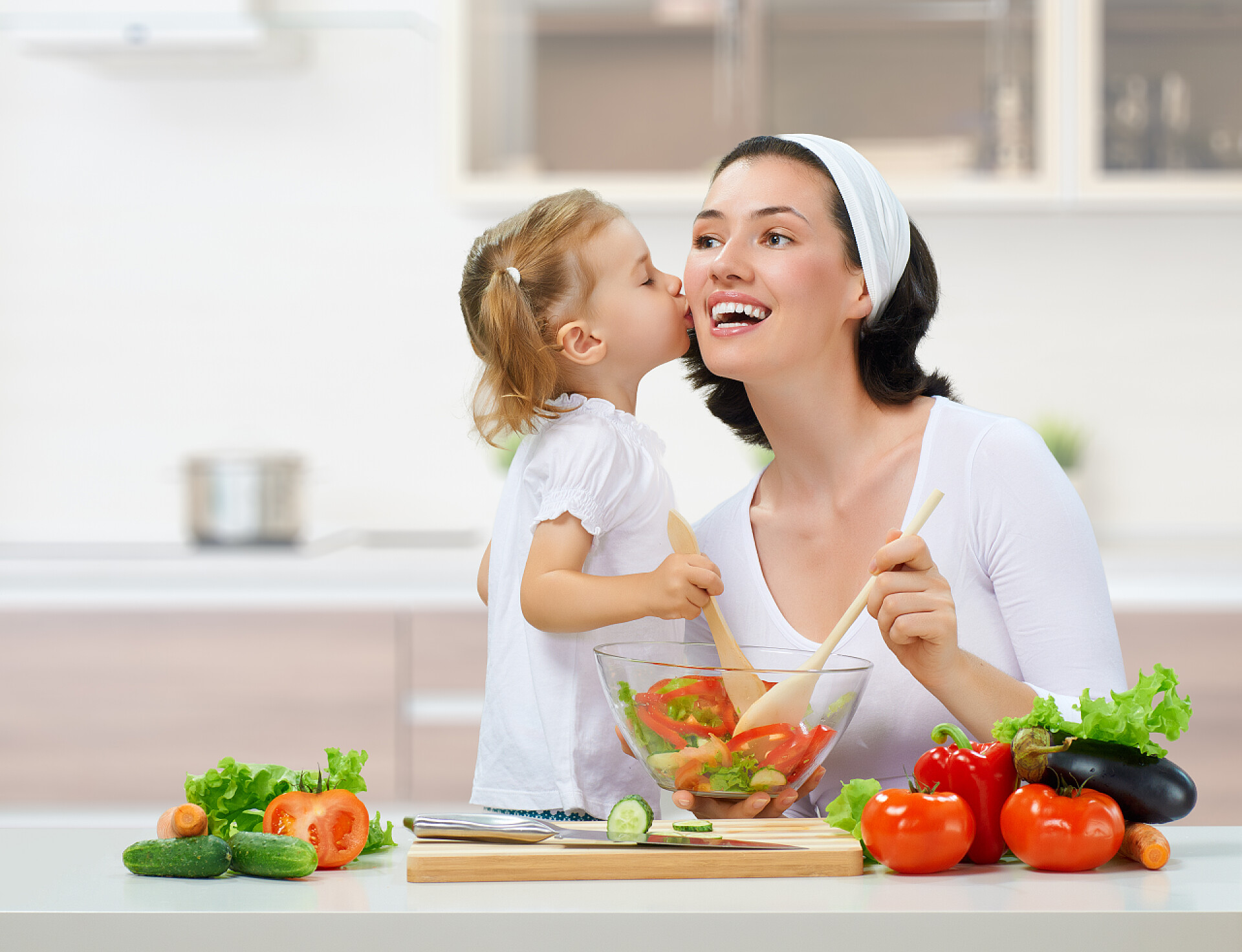 女孩在厨房亲吻她的妈妈健康食品