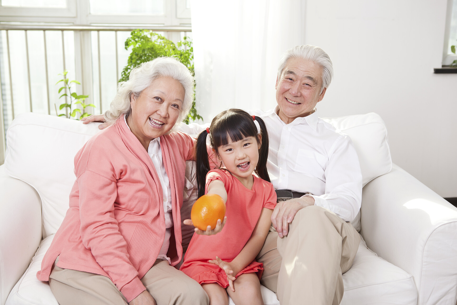 爷爷奶奶和孙女坐在白色的沙发上夫妇与孙女