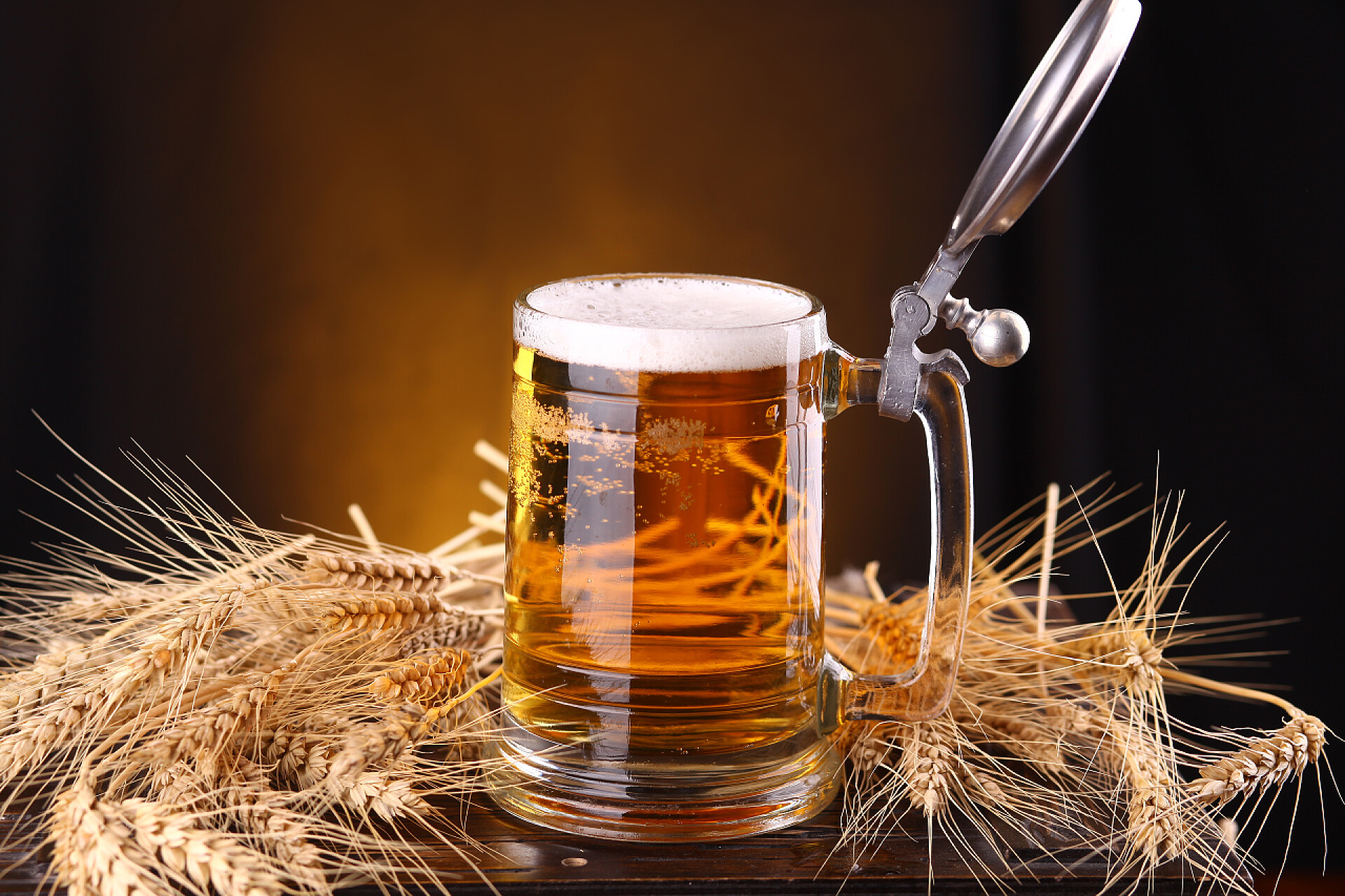 手柄杯子装满啤酒放在麦穗旁杯啤酒柜子上