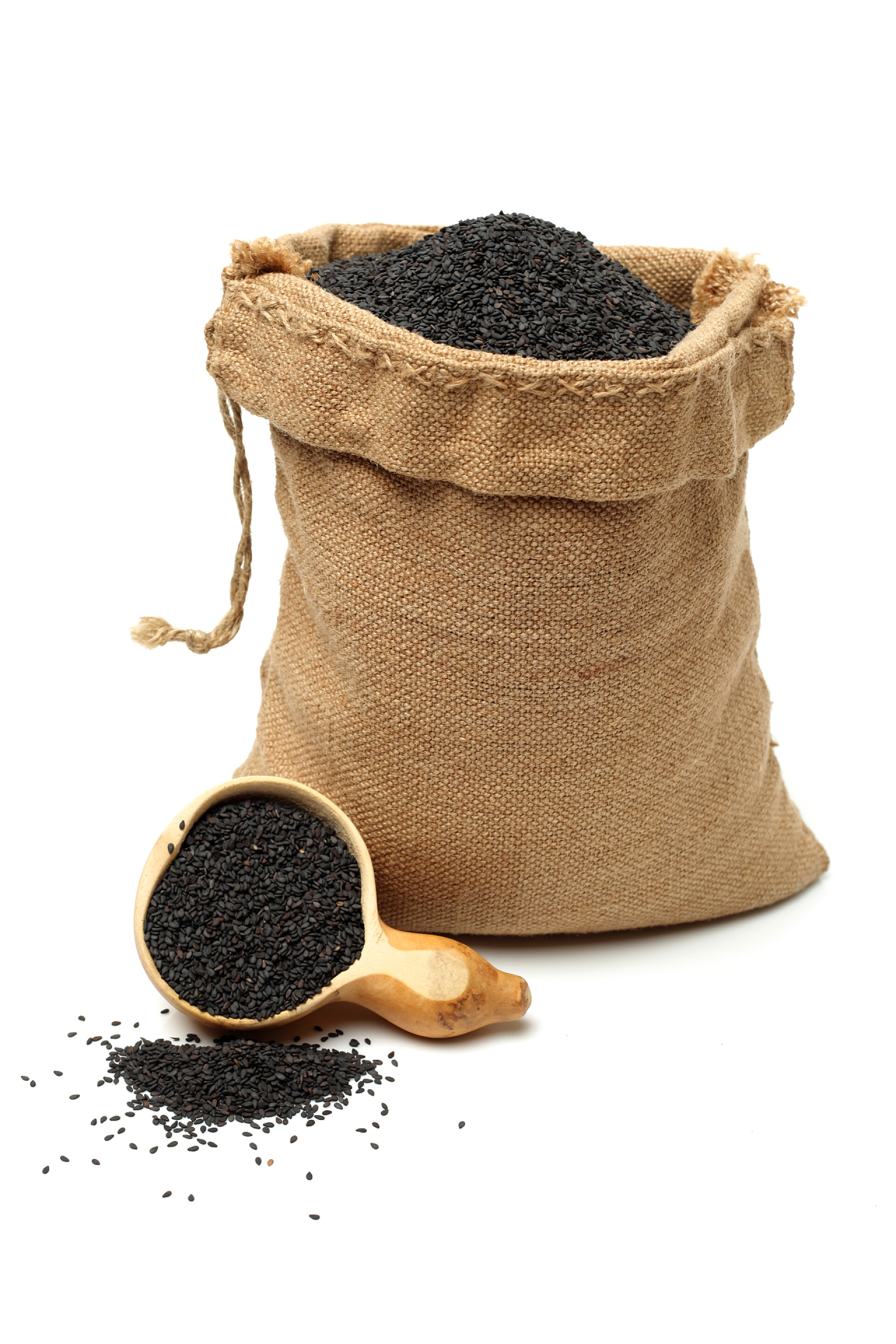 白色背景上放满黑芝麻的麻袋和木勺黑芝麻的包