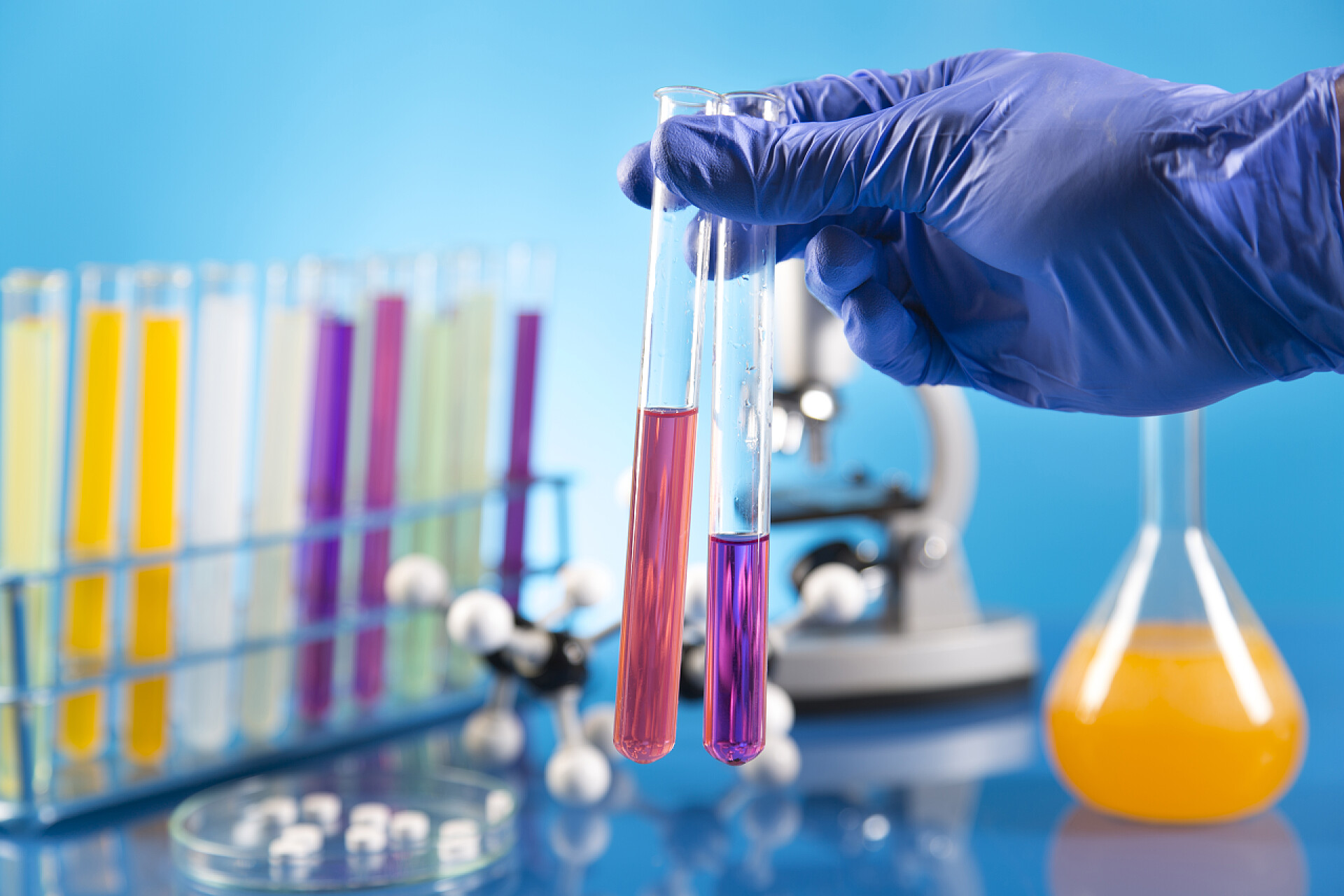 一只手拿着试管正在做生物学实验工作场所现代分子生物学实验室测试在蓝色背景