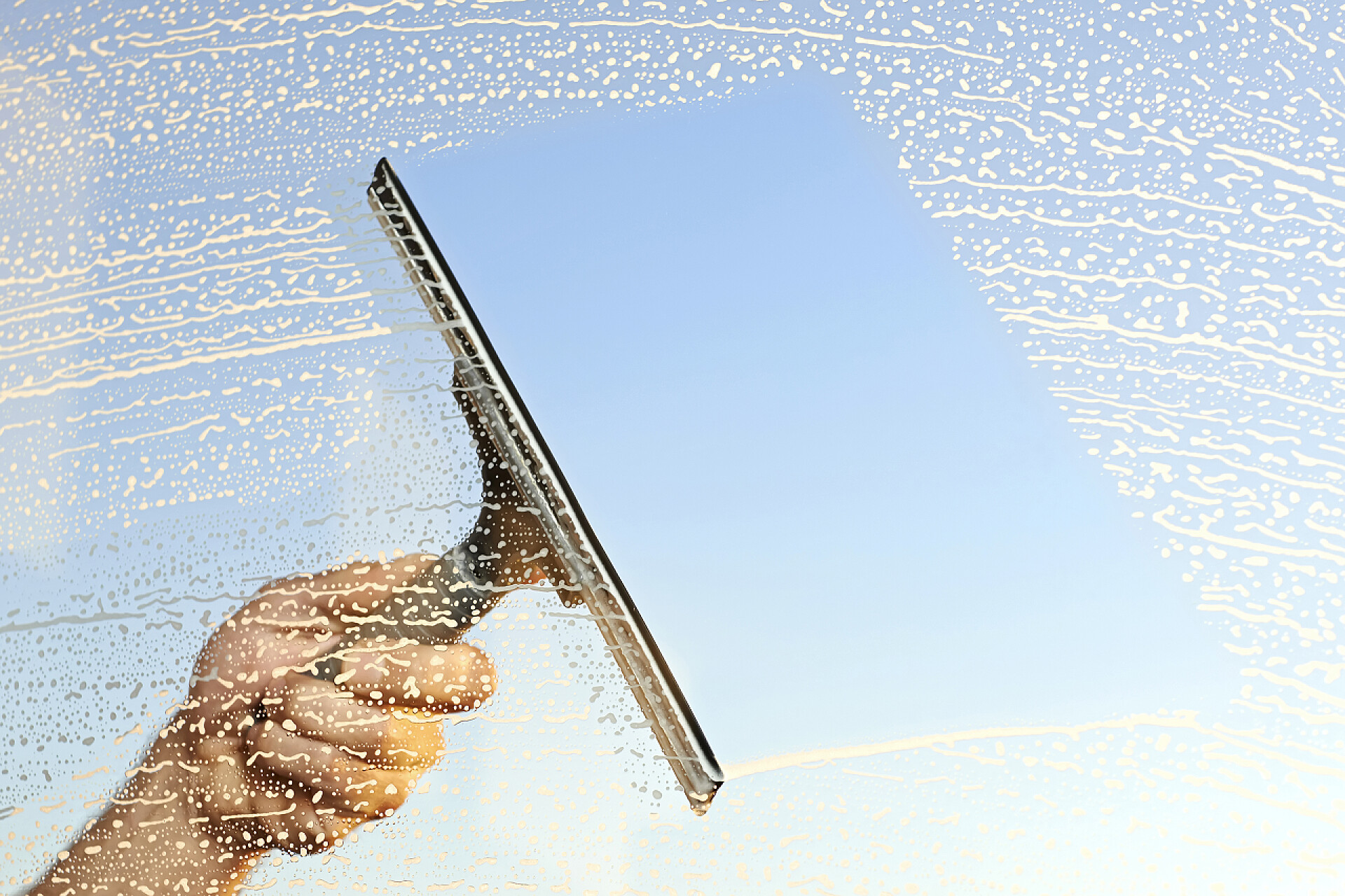 一只手在用雨刮器清洁窗户清洗视窗