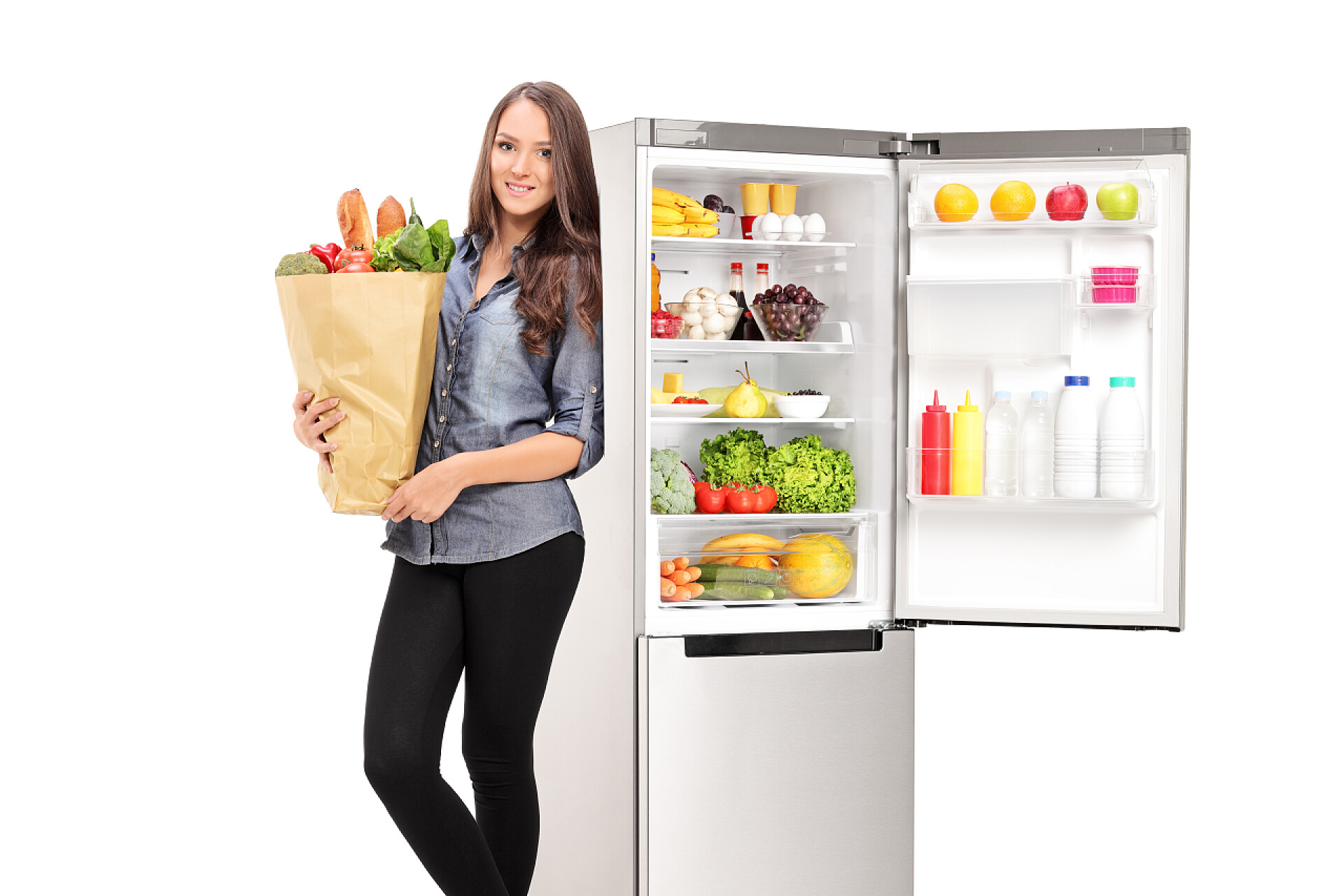 家庭主妇购买了满满一冰箱食物和一大袋食物女子手持杂货袋