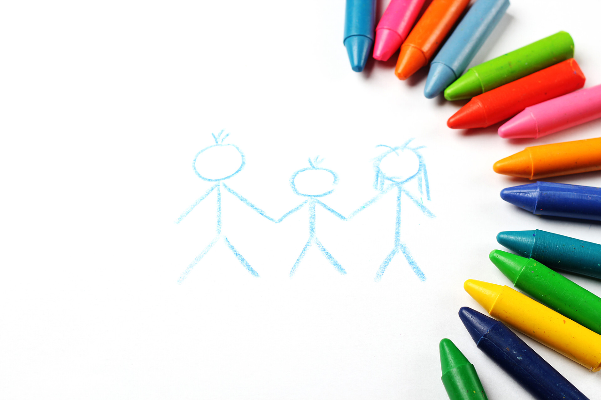 白色背景上的蜡笔石油蜡笔蜡笔躺在纸上，画的家庭