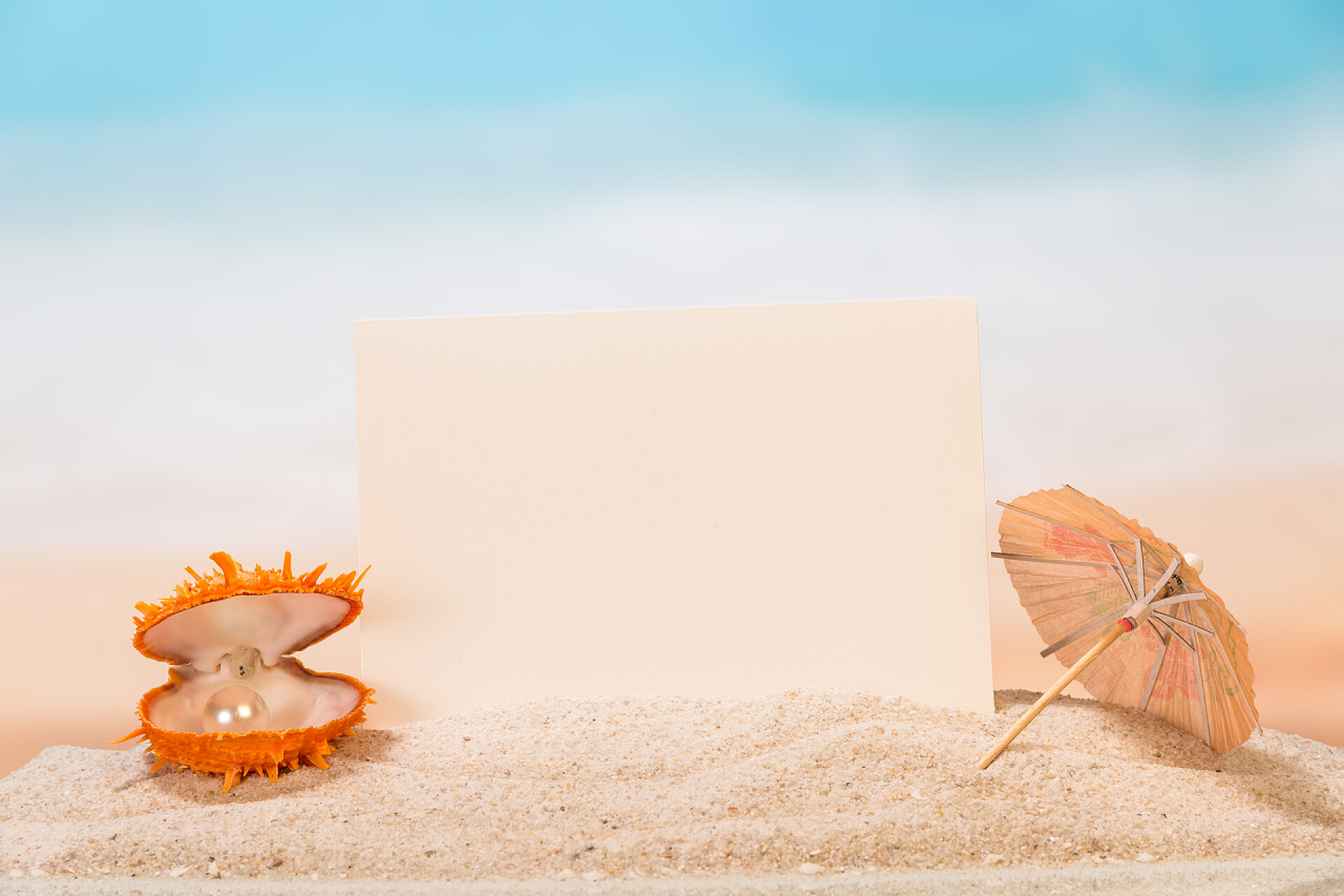 沙滩背景上珠贝壳和信封空白卡、 一把雨伞和壳