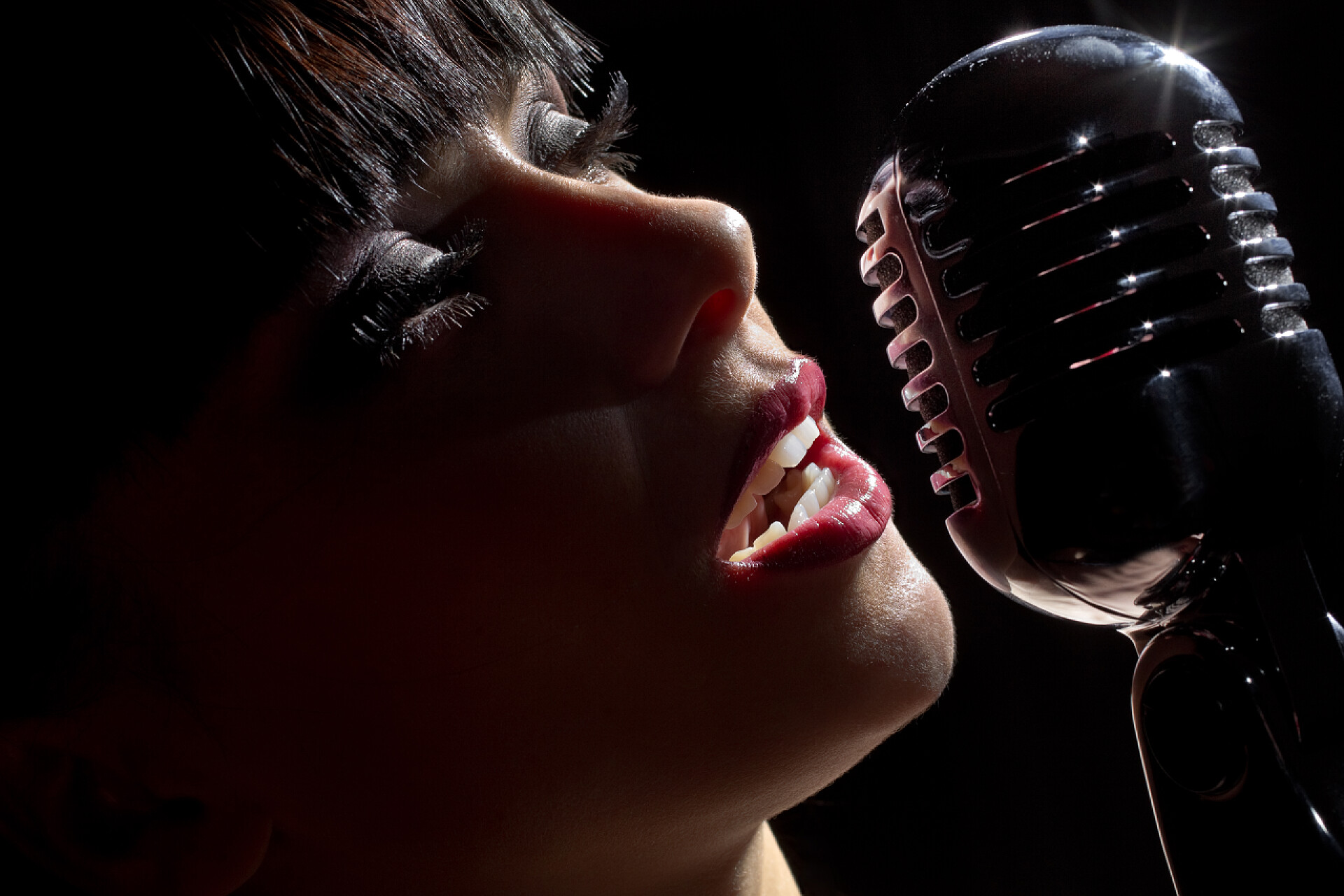 黑色的背景上在麦克风前的女性歌手歌手女人与麦克风