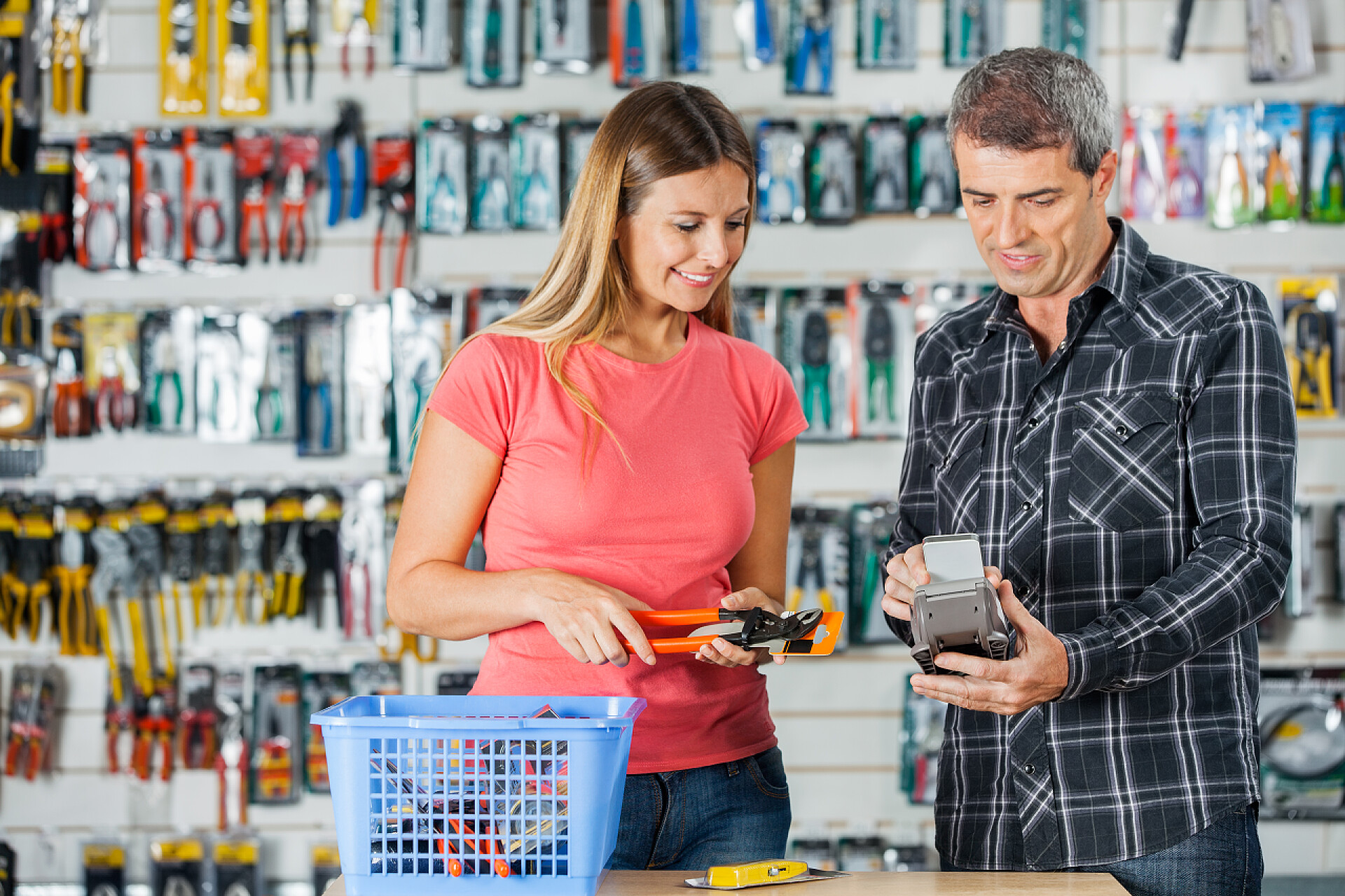 男人和女人在超市购物几个付费通过智能手机存储区中的钳子
