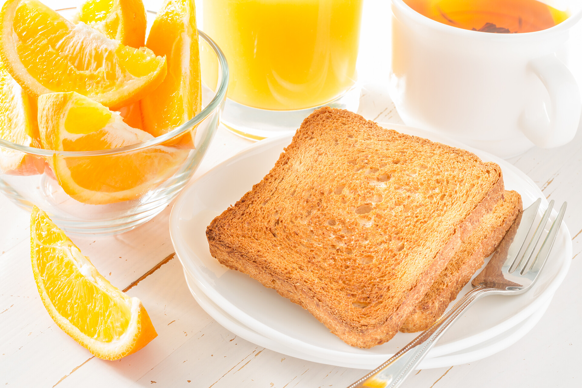 盘子里有吐司面包和橙汁白色木背景上早餐