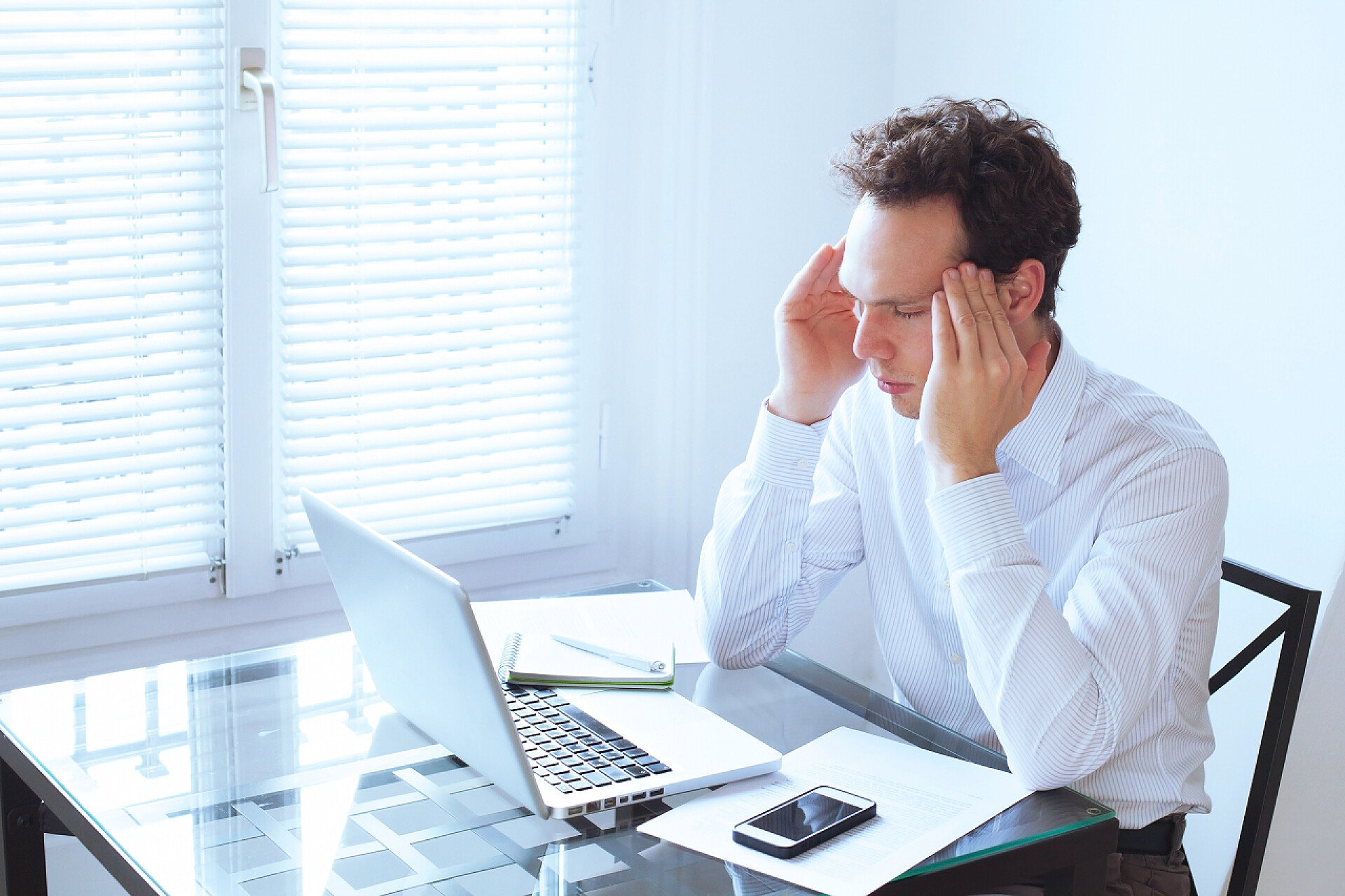 年轻男人坐在电脑前揉着脑袋年轻的人有头痛