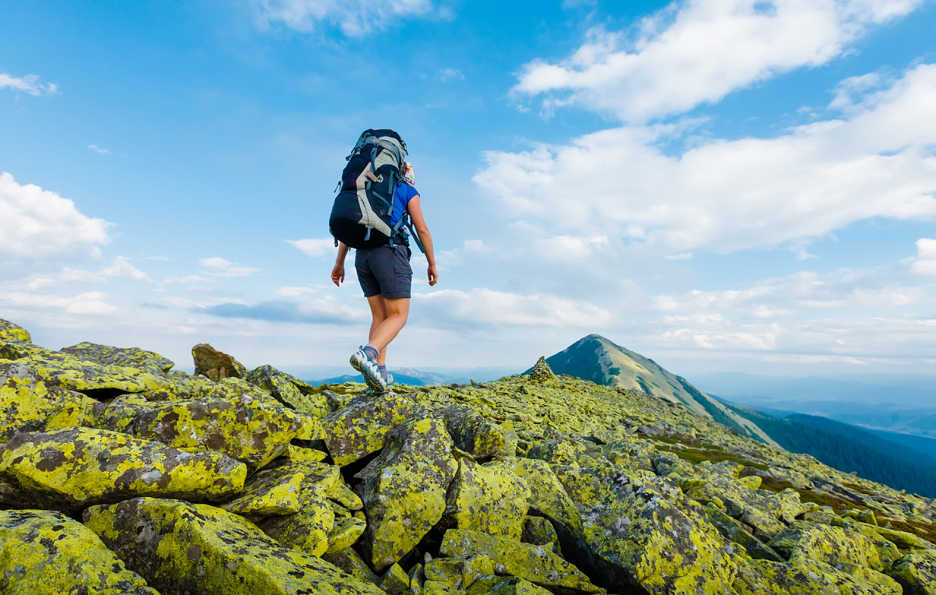 蓝天白云下徒步旅行的登山者背着背包徒步旅行者到达山峰的峰会。成功的自由和幸福成就在山中。活跃的运动概念.